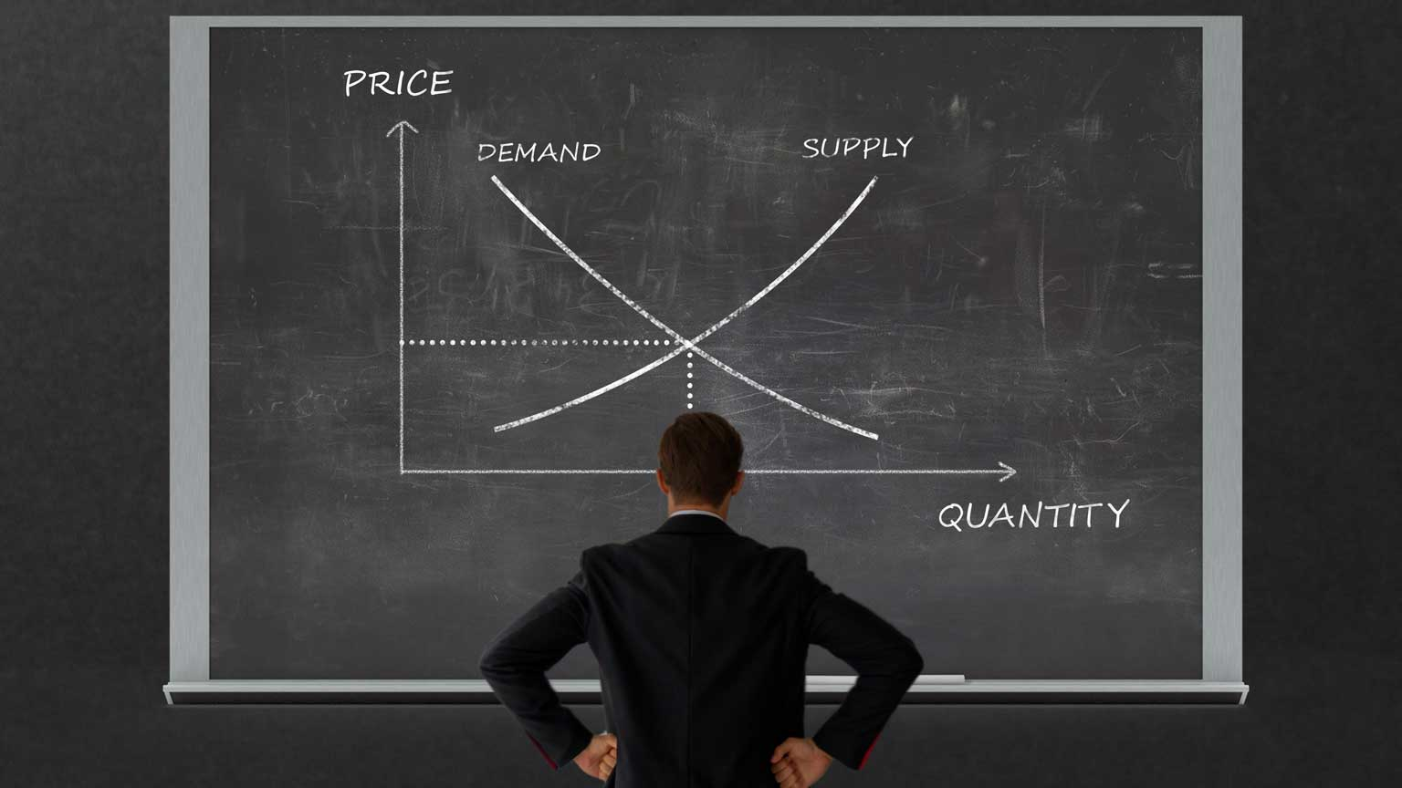 Man contemplating supply and demand on a blackboard