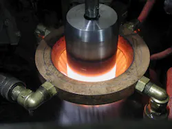 This shaft is undergoing induction hardening. Localized heating on the shaft (red/white glow) is immediately followed with a sprayed-water quench that rapidly cools it. This shaft is undergoing induction hardening. Localized heating on the shaft (red/white glow) is immediately followed with a sprayed-water quench that rapidly cools it.