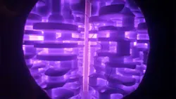 A part being ion nitrided in a vacuum chamber. The purple glow stems from a plasma discharge around the part. A part being ion nitrided in a vacuum chamber. The purple glow stems from a plasma discharge around the part.