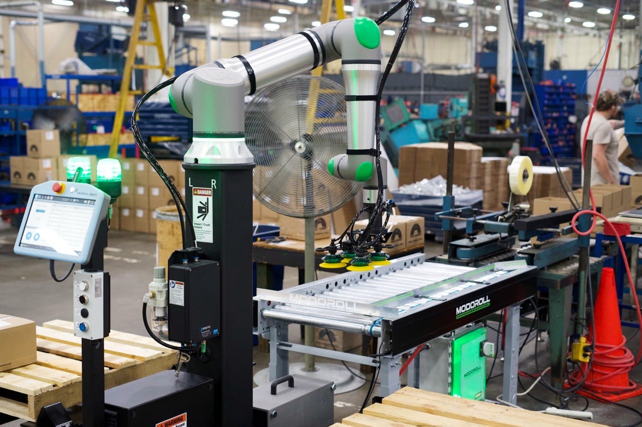 A MODOPAL C60, a collaborative robotic palletizer integrated with the MODOROLL conveyor, increases efficiency, reduces labor costs, and improves safety by automating the stacking and organizing of products on pallets.
