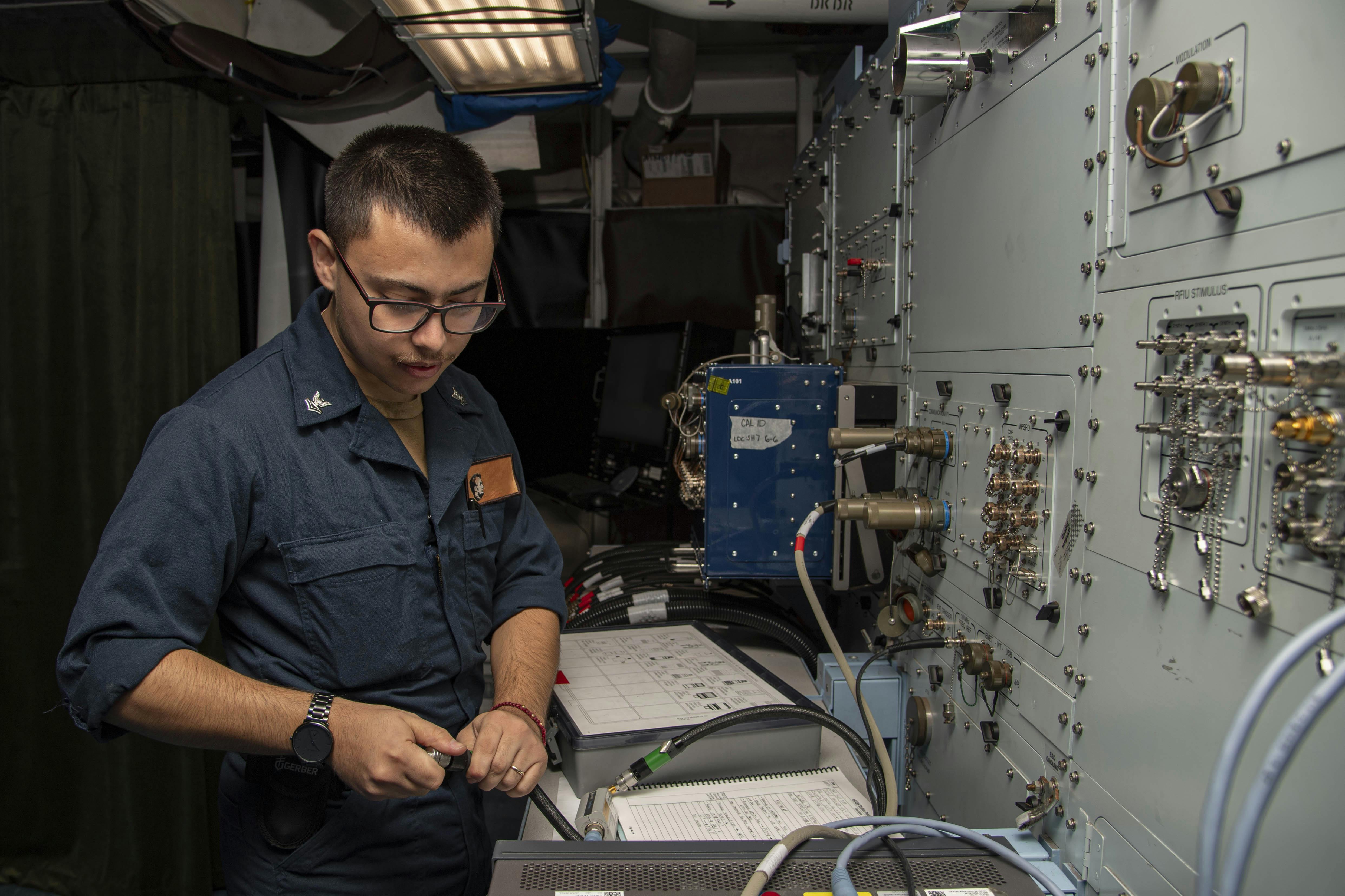 A U.S. Navy aviation electronics technician calibrates eCASS test equipment aboard the aircraft carrier USS Abraham Lincoln (CVN 72)