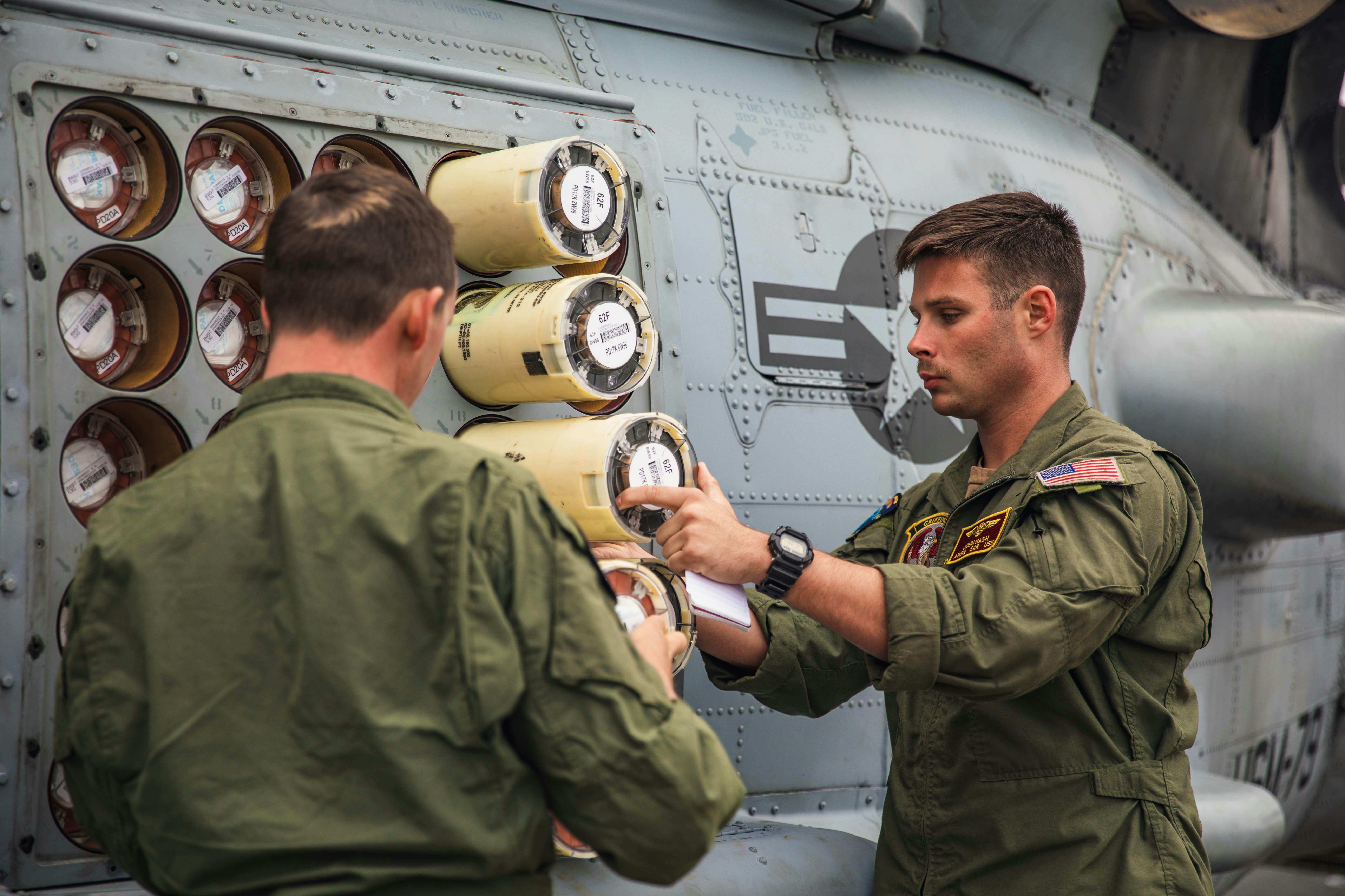 Naval air crewmen inspect and load sonobuoys into an MH-60R Sea Hawk helicopter on the flight deck of the Arleigh Burke-class guided-missile destroyer USS Paul Ignatius (DDG 117).