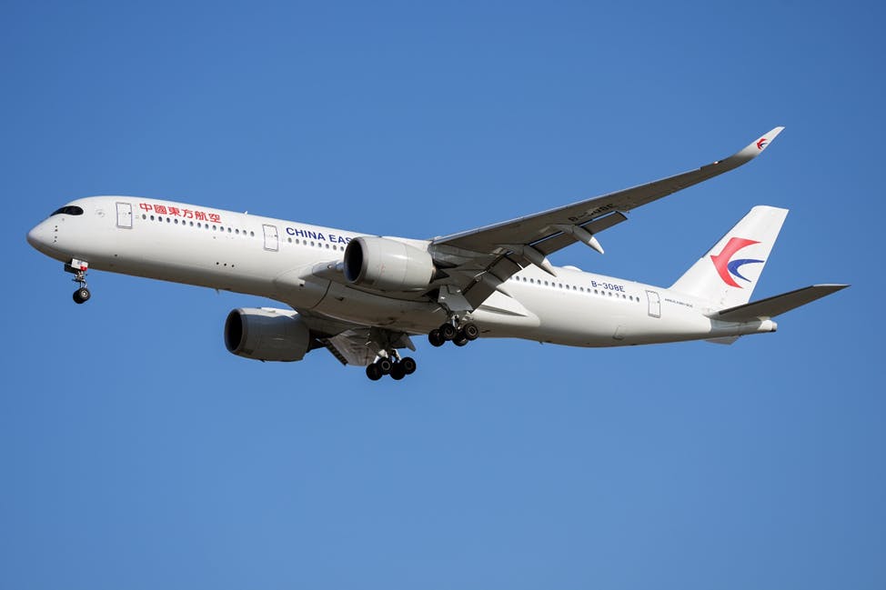 A China Eastern Airlines A350 flies with a blue sky in the background.
