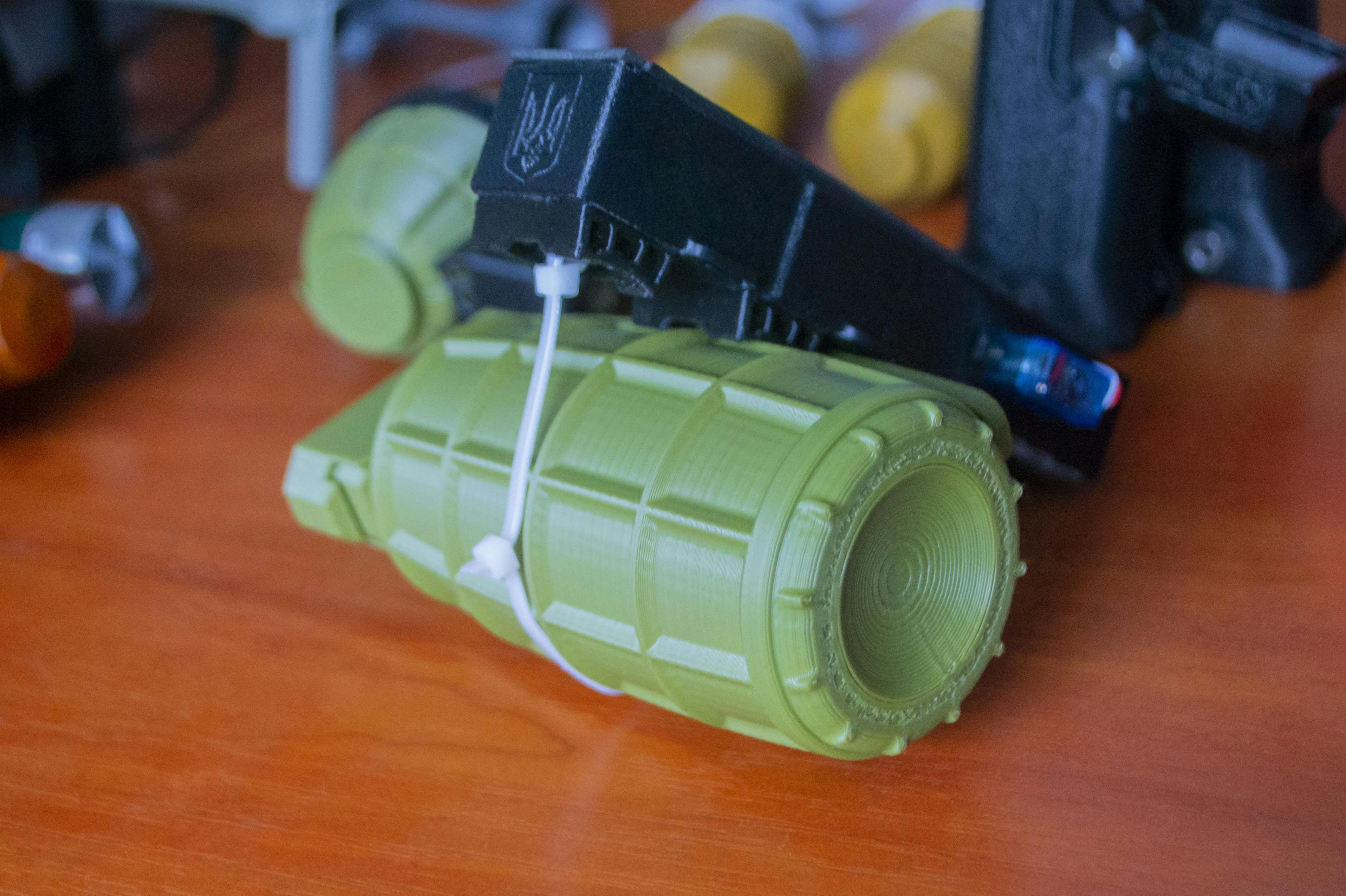 Small models of grenade defensive weapon printed on 3D printer from molten plastic on table.