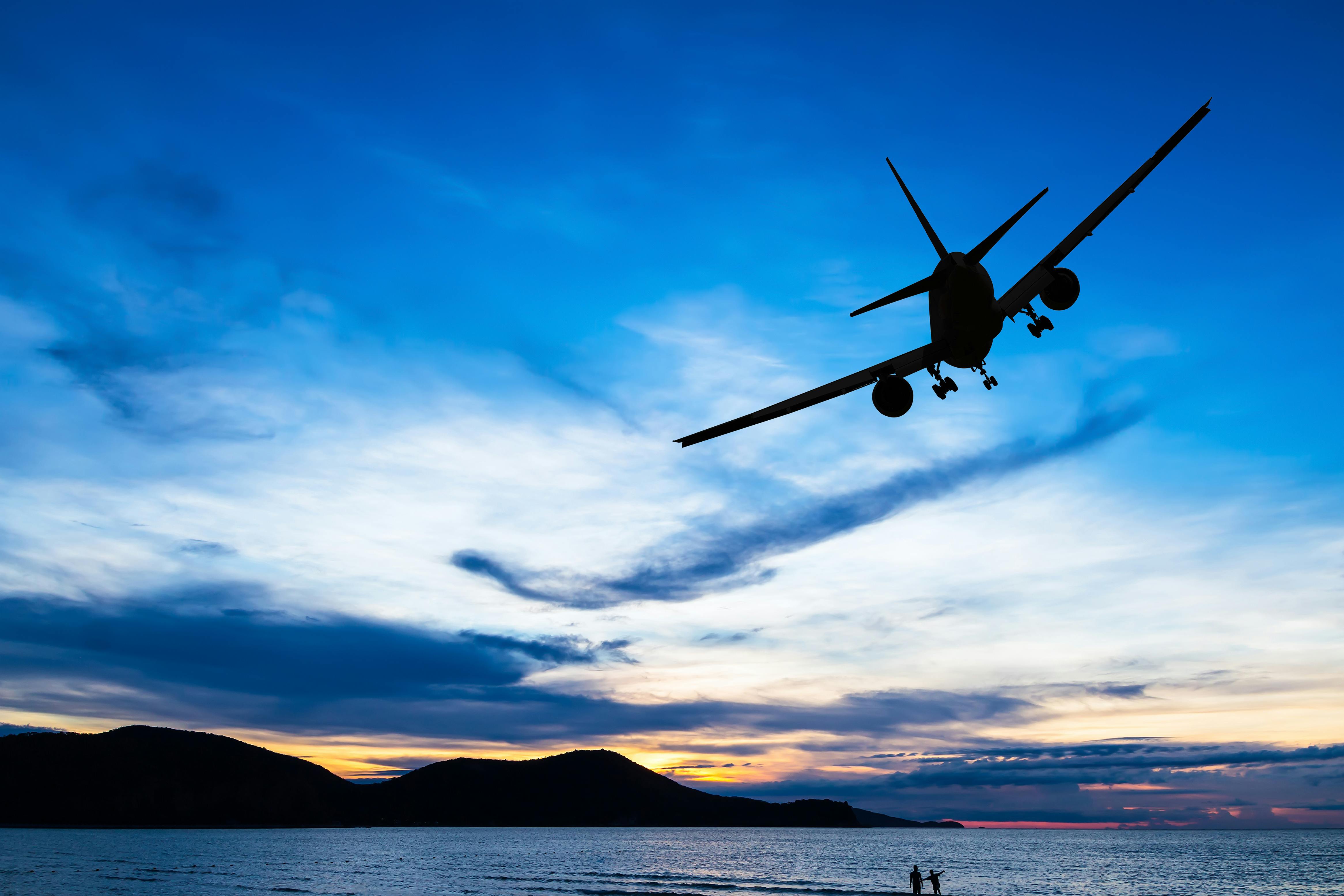 A passenger aircraft silhouetted by a sunset