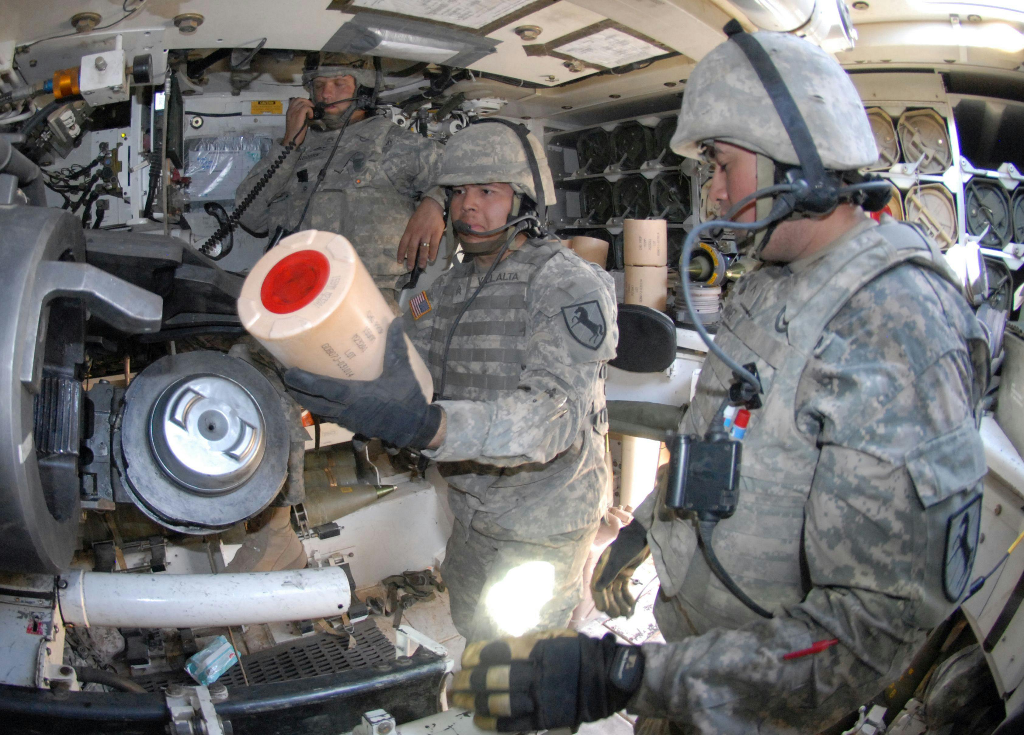 Army National Guardsmen load charges into the tube of an M-109A6 Paladin 155-millimeter self-propelled howitzer at National Training Center, Fort Irwin, Calif.