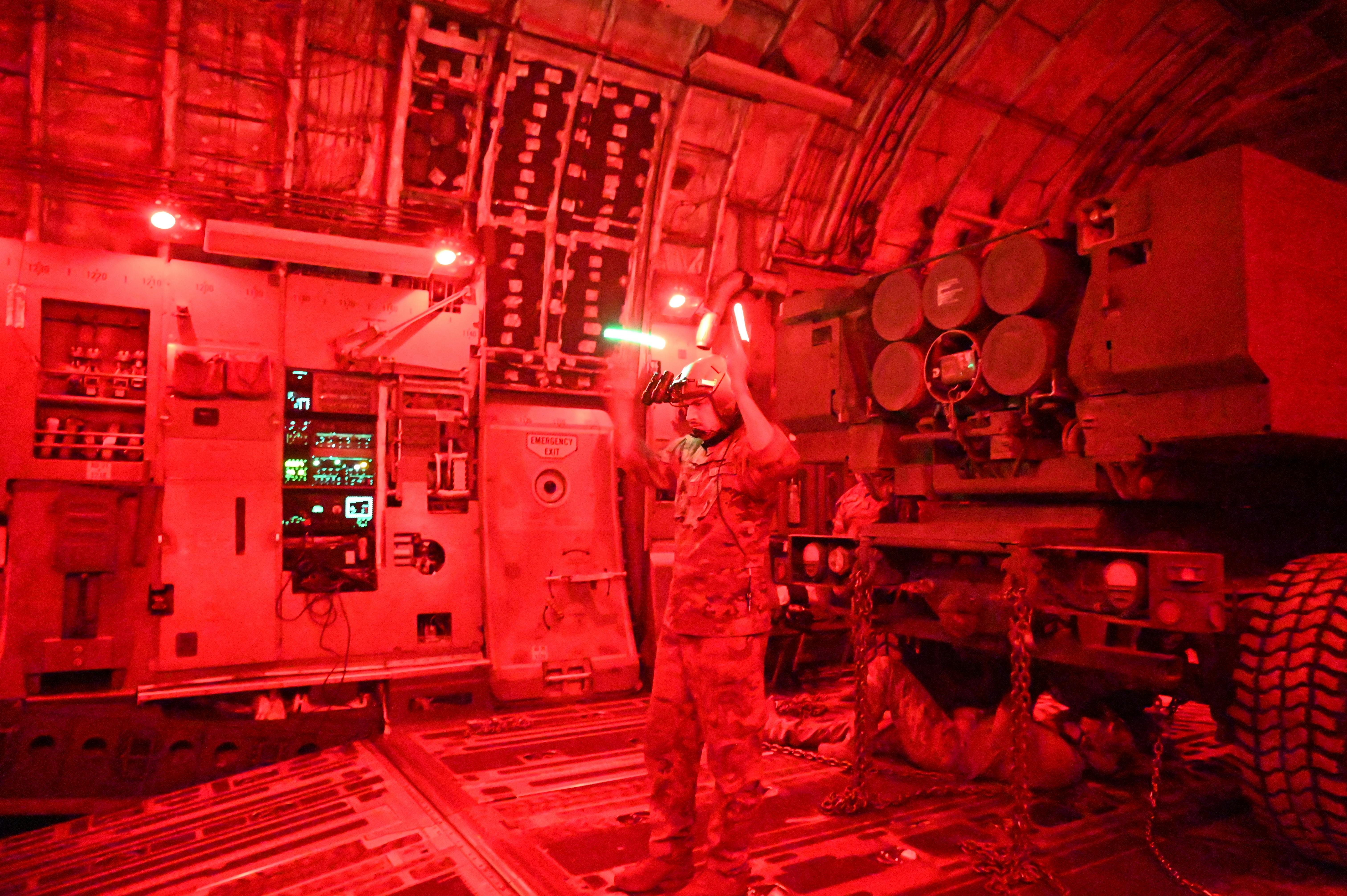 A U.S. Air Force loadmaster places a HIMARS launcher and artillery crews aboard a C-17 Globemaster III cargo jet using night-vision goggles during an exercise last March.