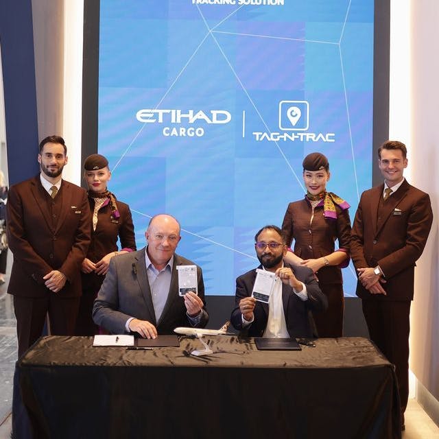 Businesspeople pose with the SmartTrack technology at a table with company logos behind them