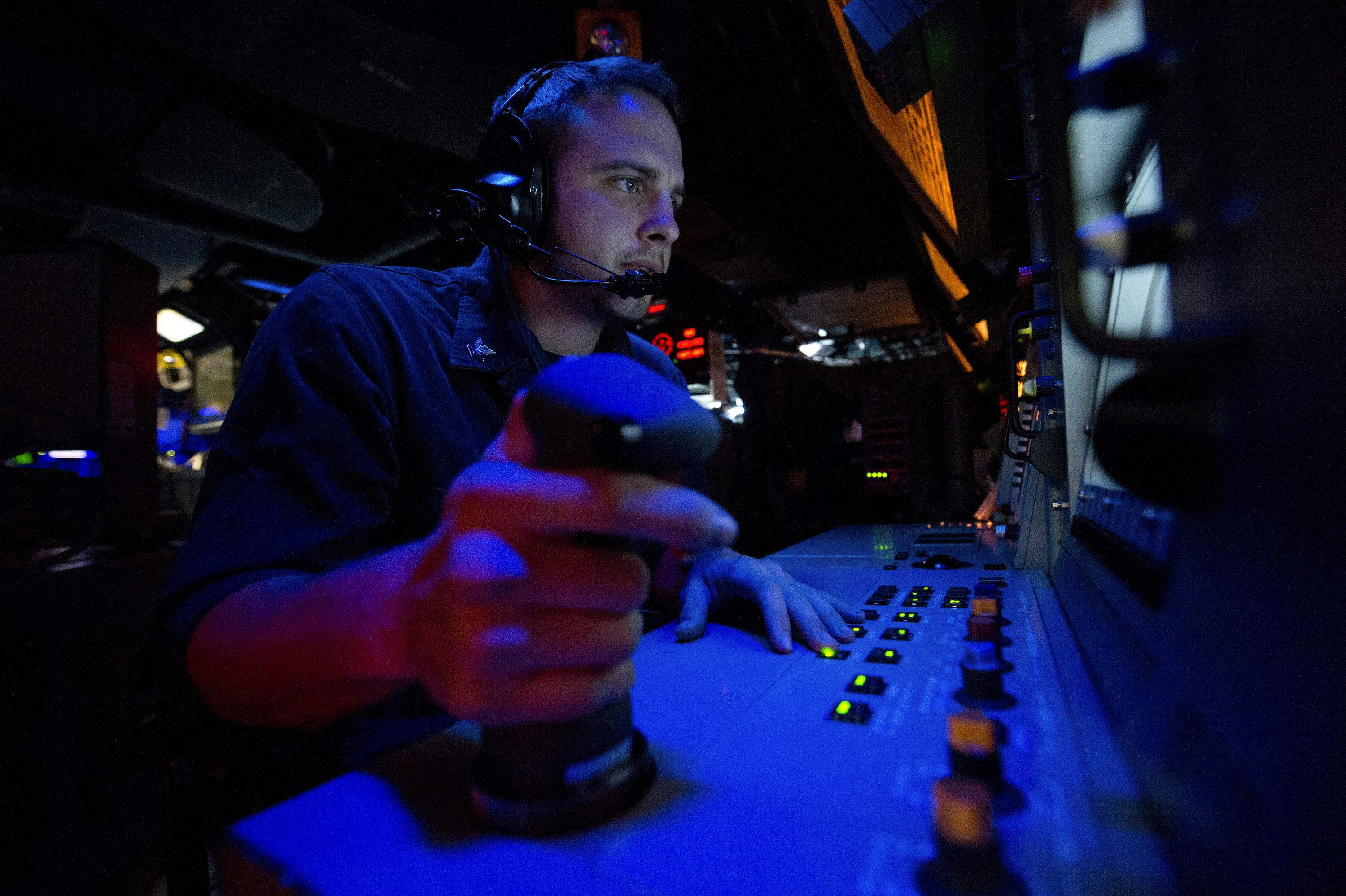 A Navy fire controlman stands watch in the combat information center aboard the guided-missile destroyer USS Arleigh Burke (DDG 51).