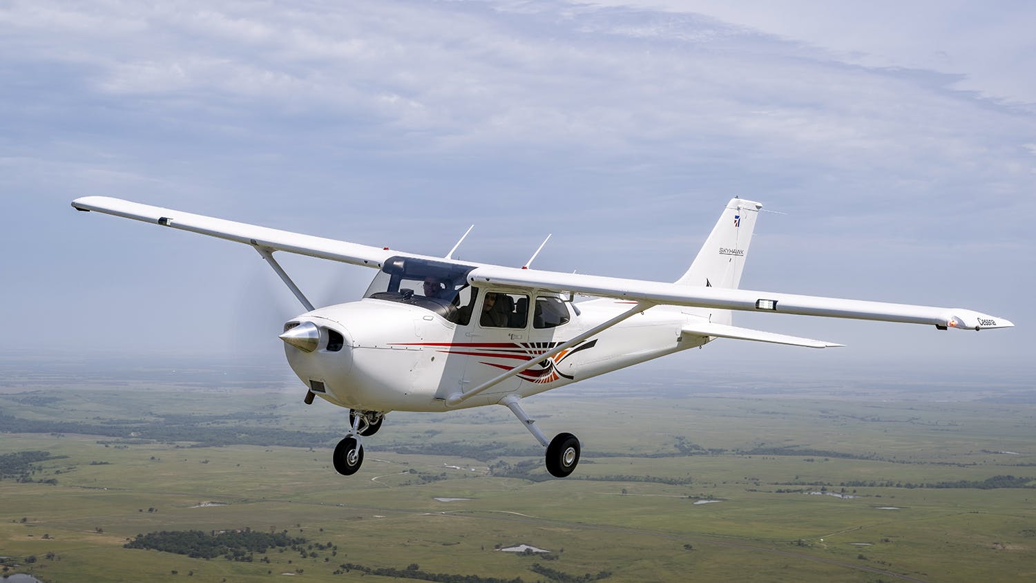 The Cessna Skyhawk flying over a green landscape