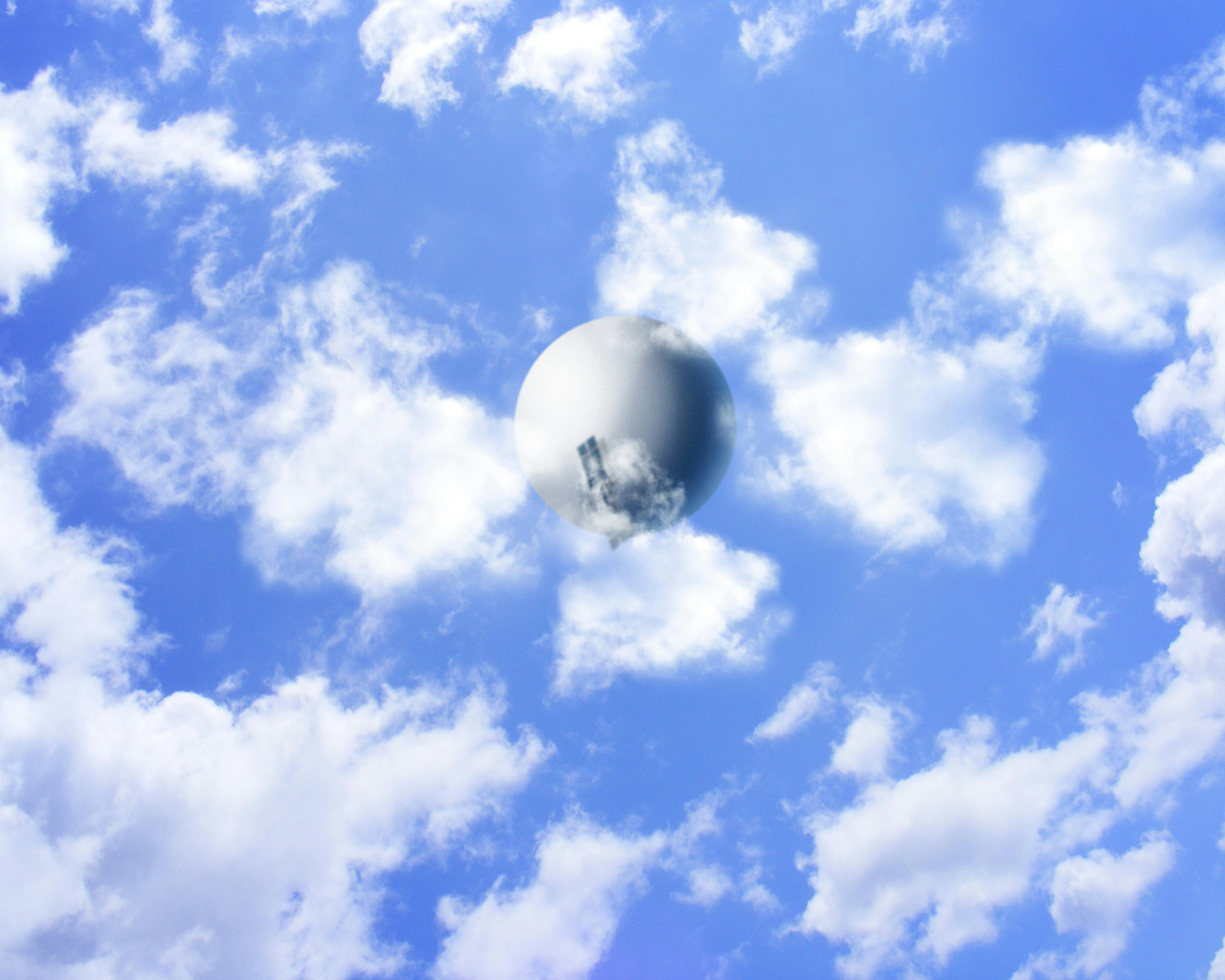 A weather balloon floats below clouds as shot from below.