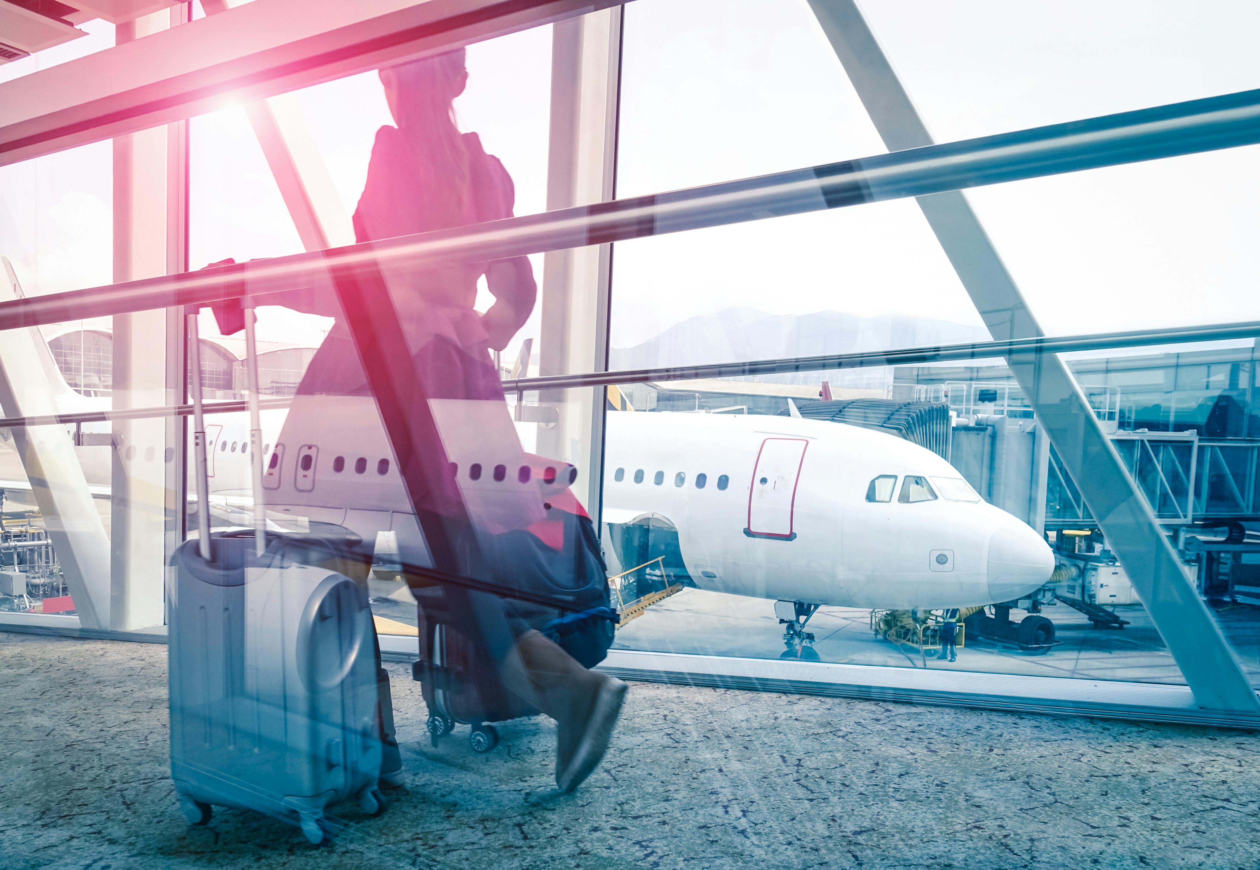 A stylized image of a passenger walking with a bag by an airport window.