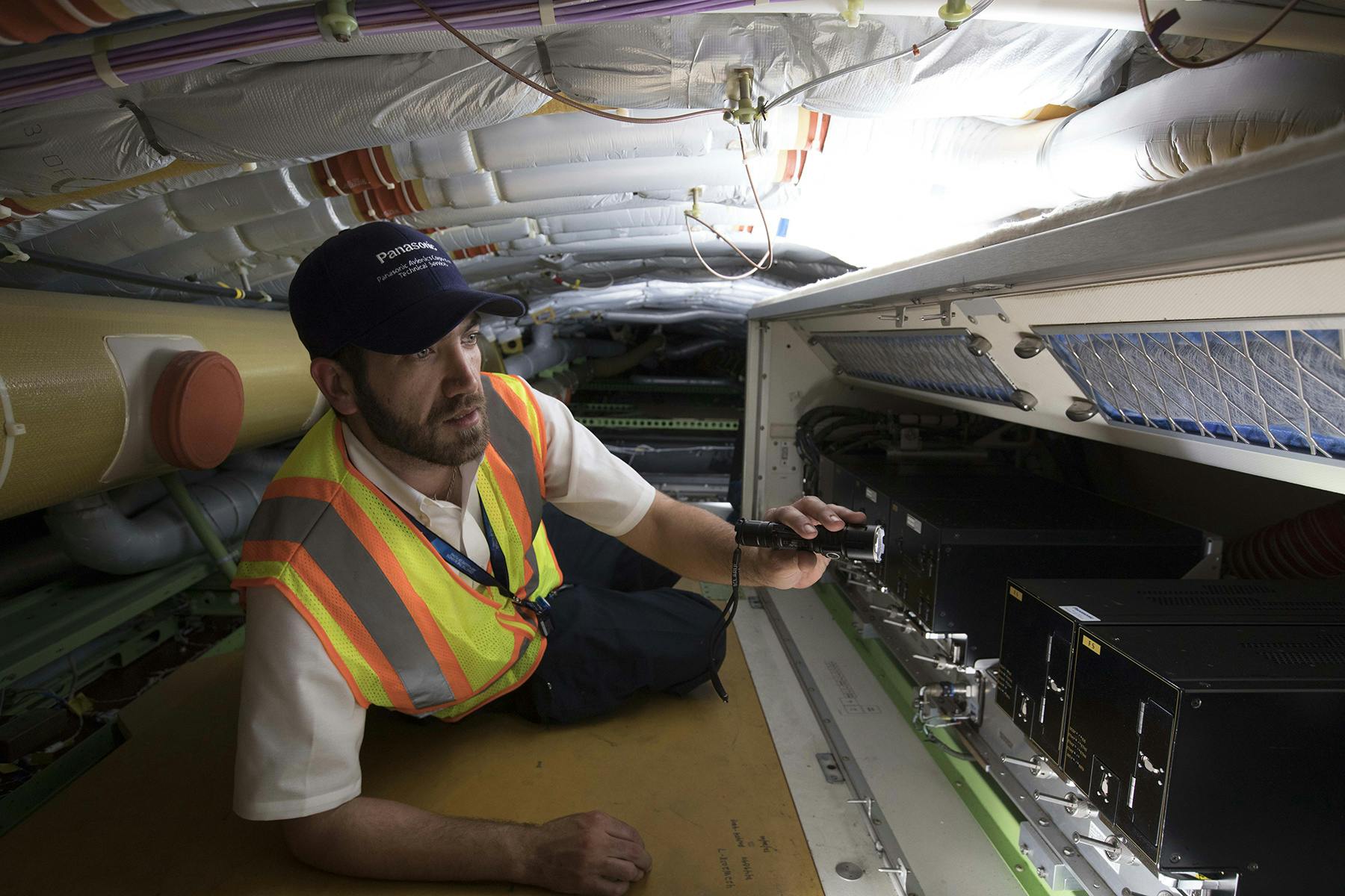 A Panasonic technician works in an airplane.