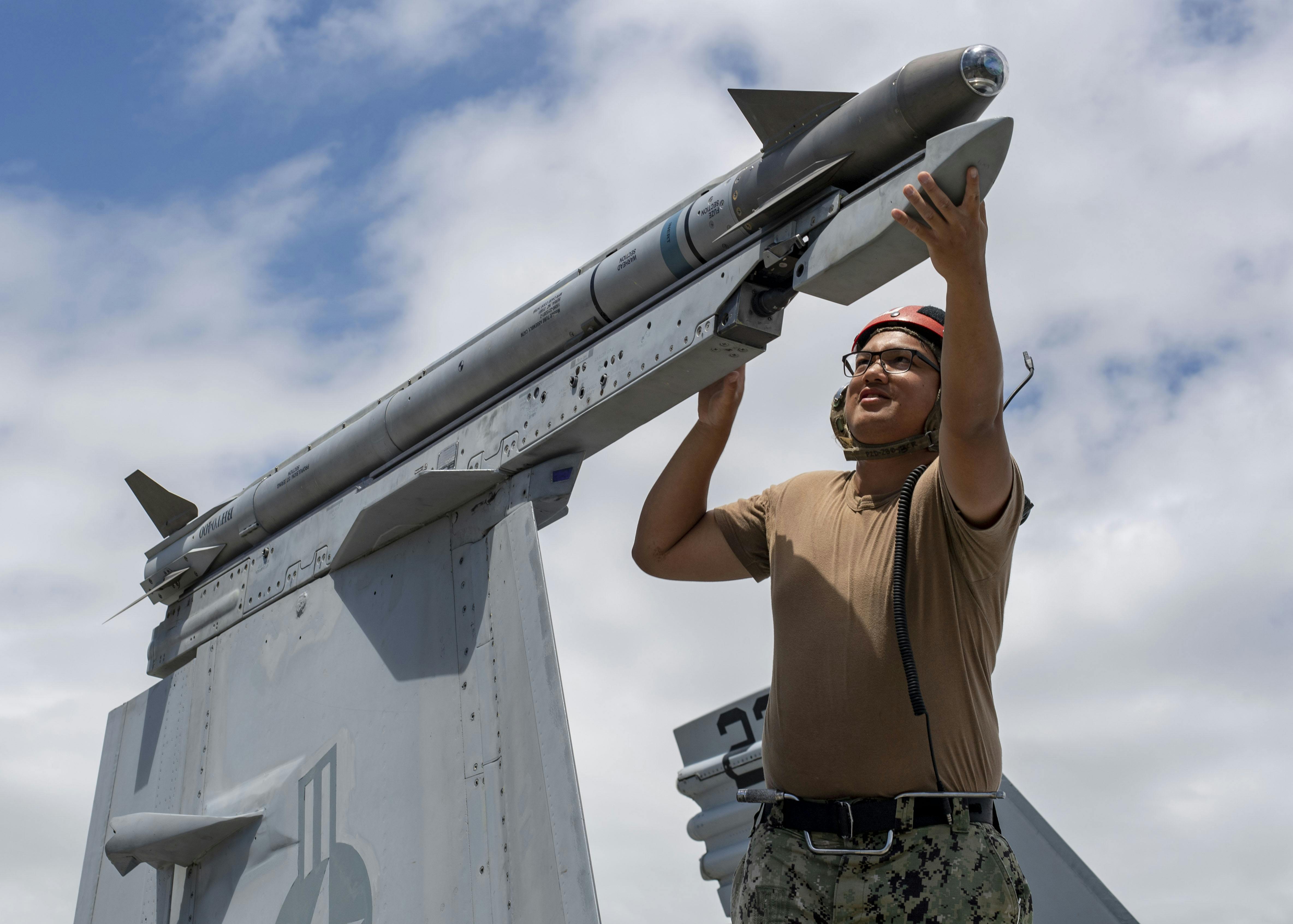 A Navy aviation ordnanceman secures an AIM-9X air-to-air missile to an F/A-18F Super Hornet during the Rim of the Pacific (RIMPAC) exercise in 2024.