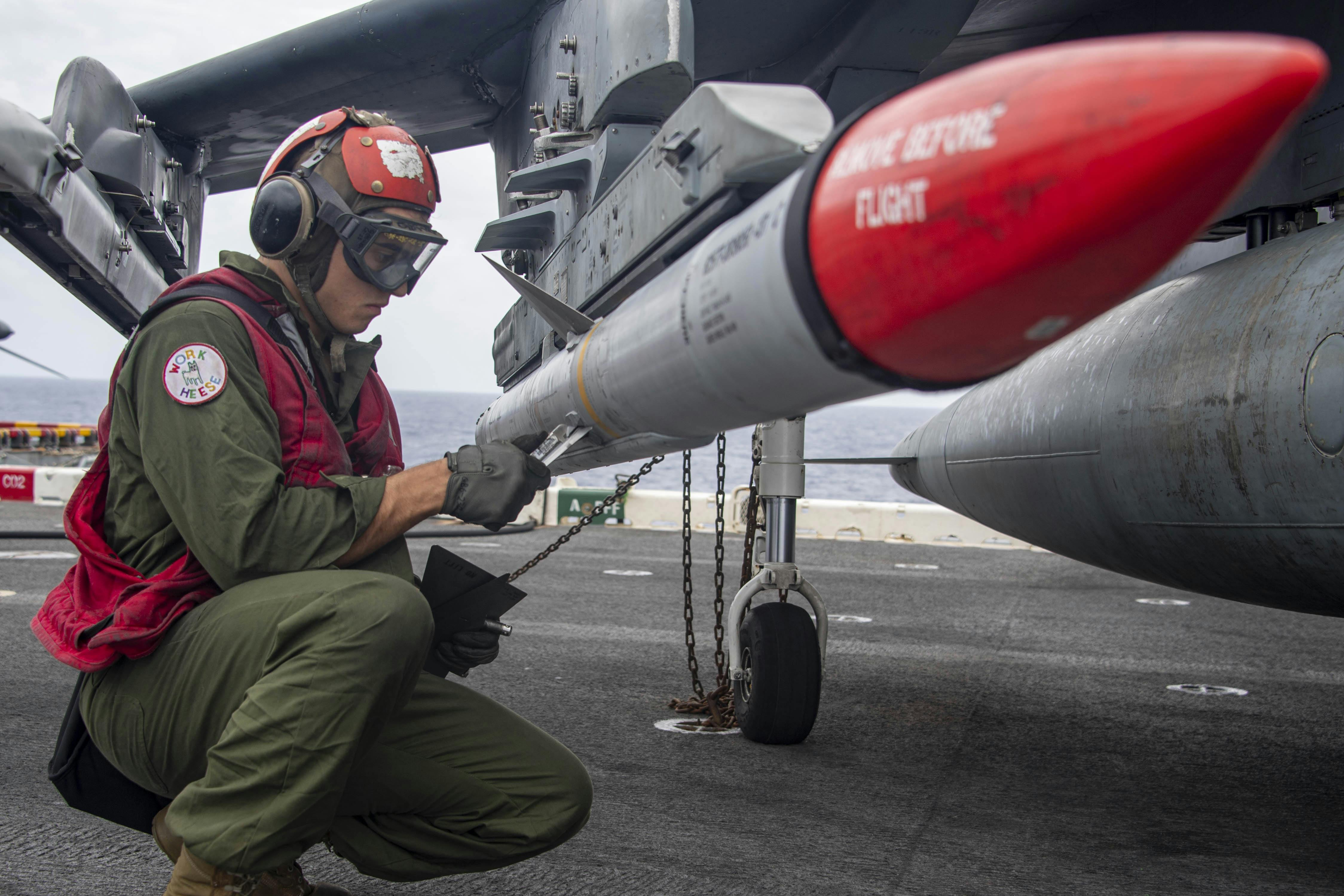A Marine Corps weapons expert loads an Advanced, Medium-Range, Air-to-Air Missile (AMRAAM), onto a combat jet aboard the amphibious assault ship USS Essex (LHD 2) in February 2022.