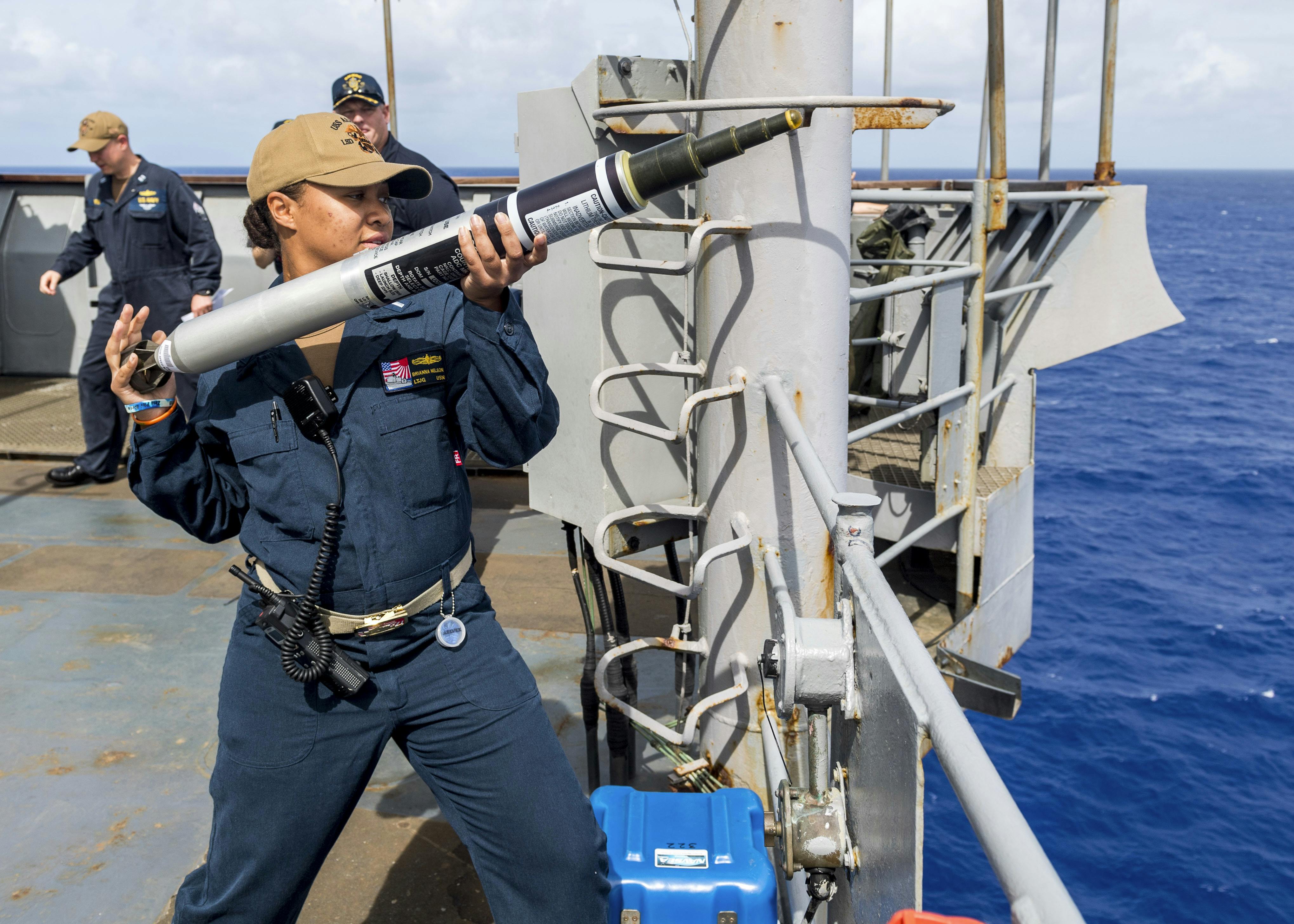 A naval officer prepares to launch an Acoustic Device Countermeasure (ADC) torpedo countermeasure from the bridge wing of the amphibious dock landing ship USS Ashland (LSD 48) during a 2019 training exercise.