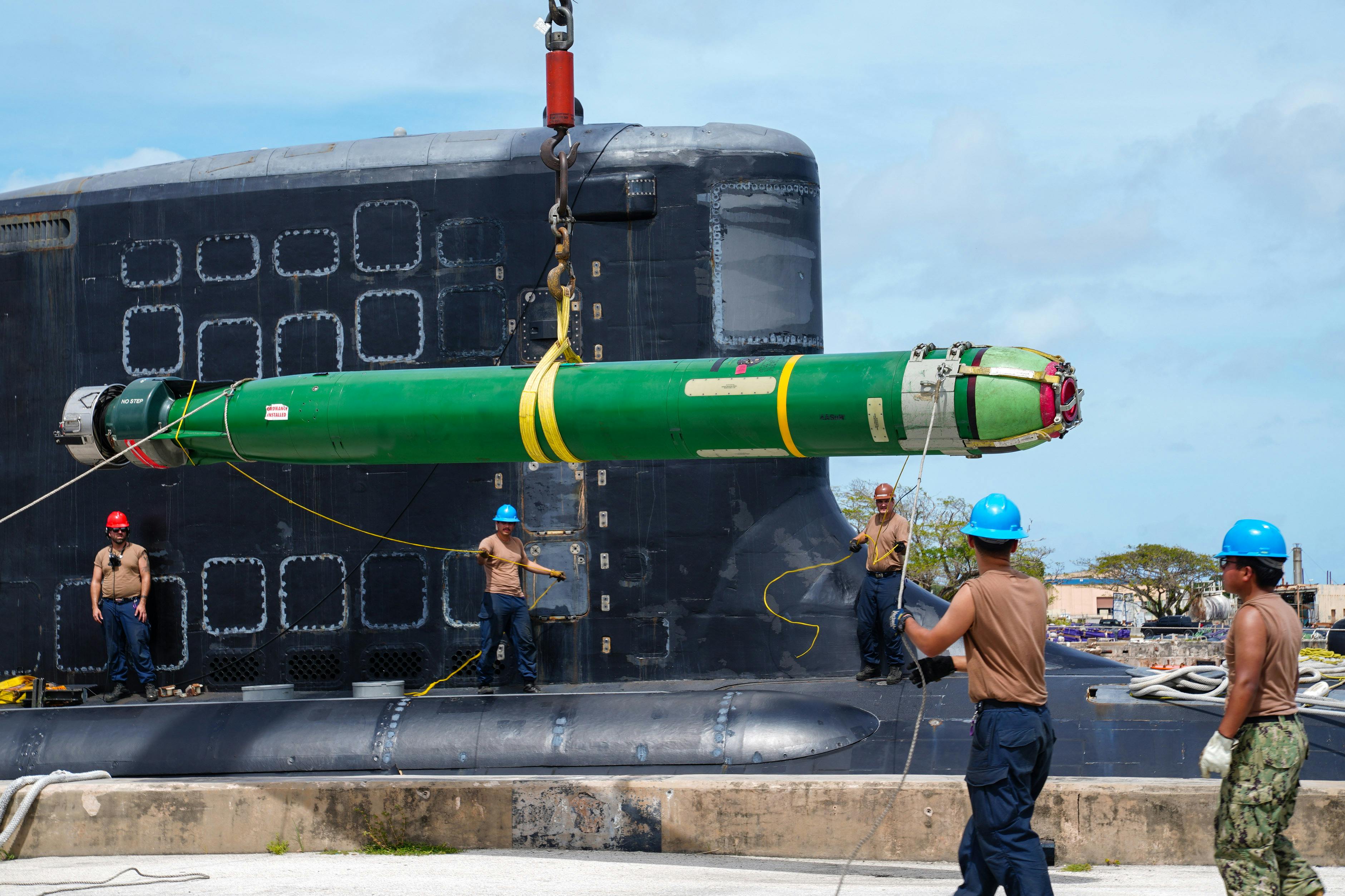 Crewmen aboard the Virginia-class submarine USS Minnesota (SSN 783) guide a Mark 48 ADCAP torpedo during a weapons offload at Guam Naval Base last February.