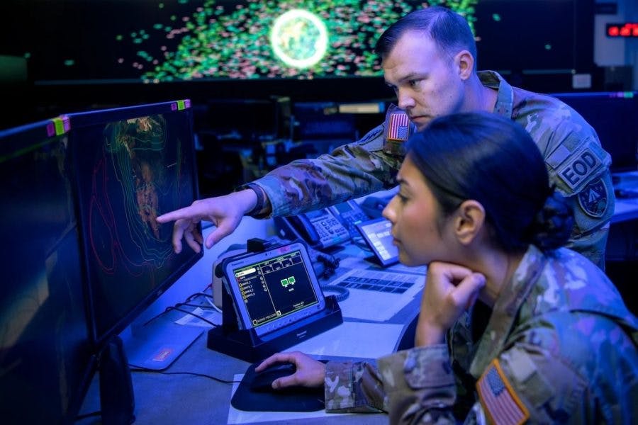 A U.S. Army mission director for the National Space Defense Center points to a screen in front of a U.S. Space Force weapons and tactics section chief at Schriever Space Force Base, Colo., in October 2022.