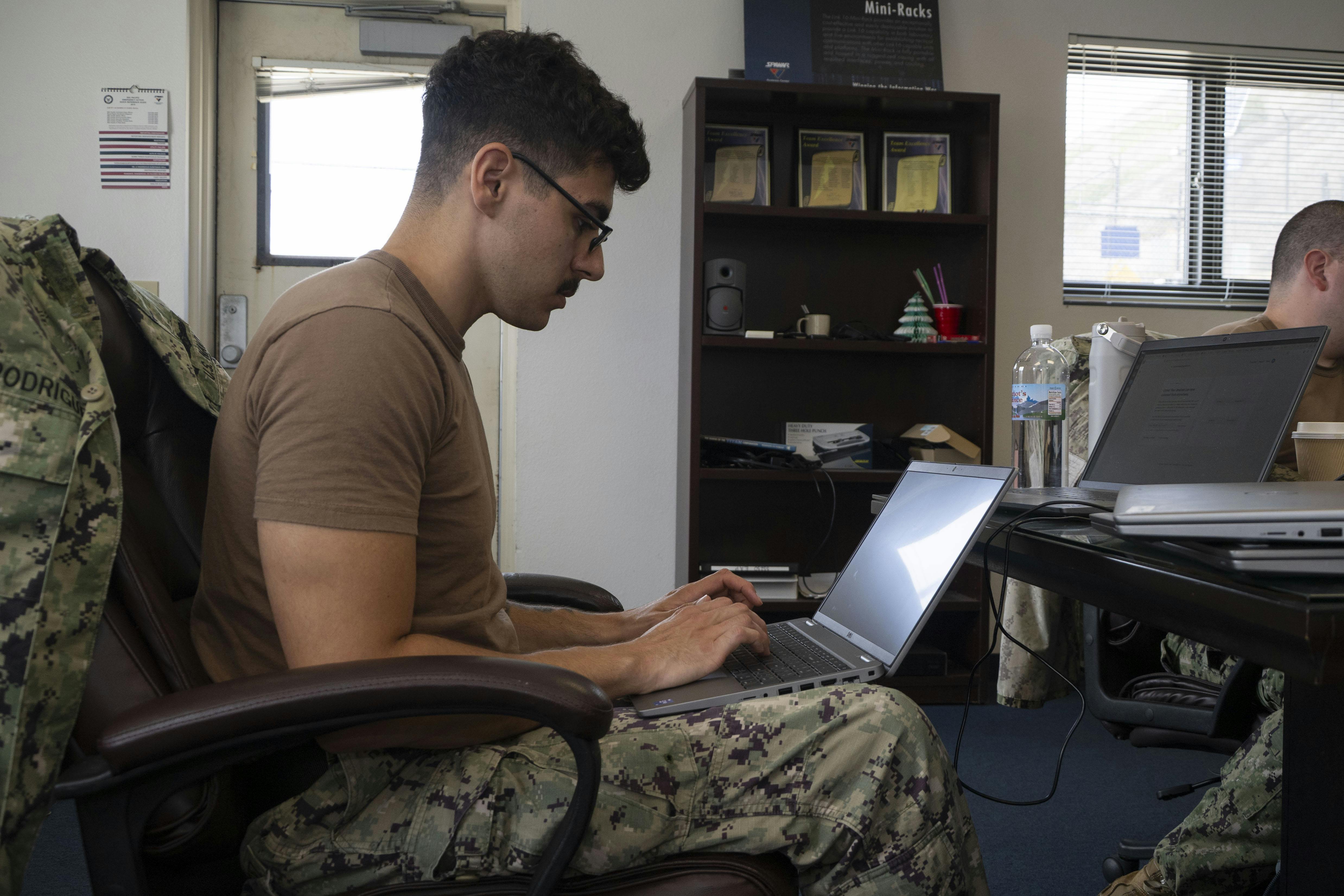 A U.S. Navy cyber warfare technician configures equipment in the Naval Information Warfare Center (NIWC) Pacific 5G lab.