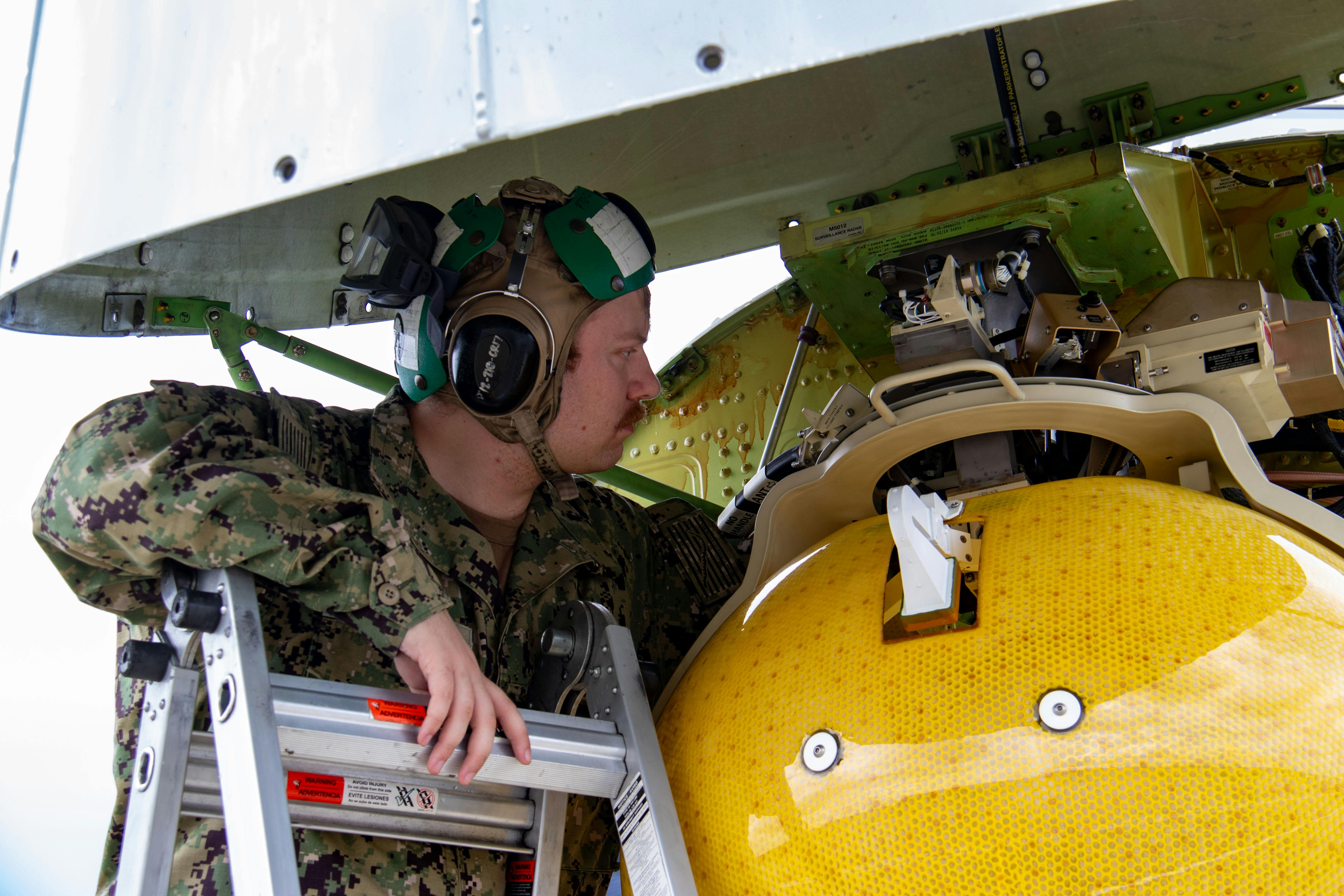A U.S. Navy aviation electronics technician performs maintenance on the AN/APY-10 radar of a P-8A Poseidon at Royal Air Force Base Lossiemouth, Scotland, in 2023.
