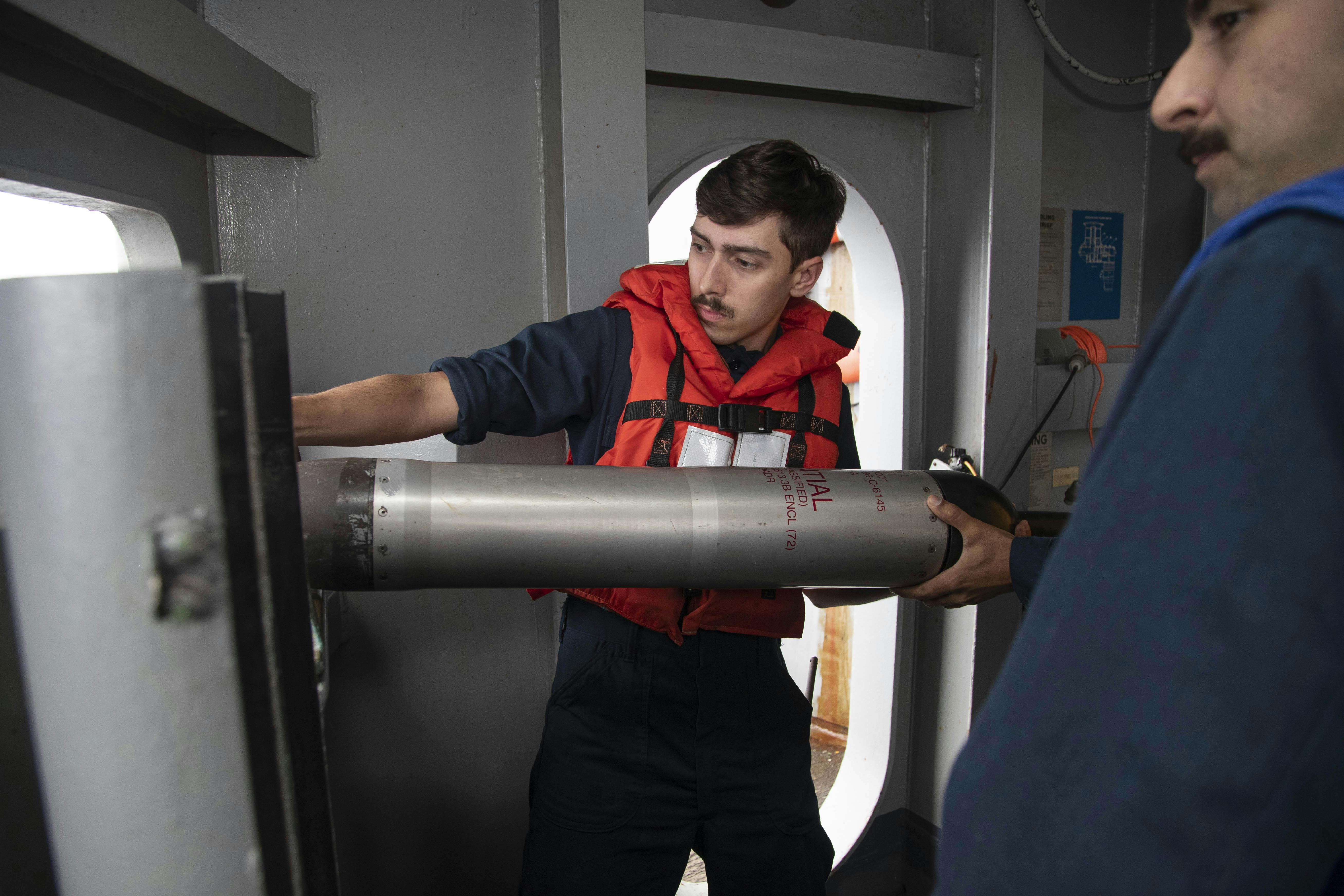 A U.S. Navy sonar technician prepares to deploy an AN/SLQ-25 Nixie torpedo counter measure system from the Nimitz-class aircraft carrier USS Abraham Lincoln (CVN 72) in 2023.
