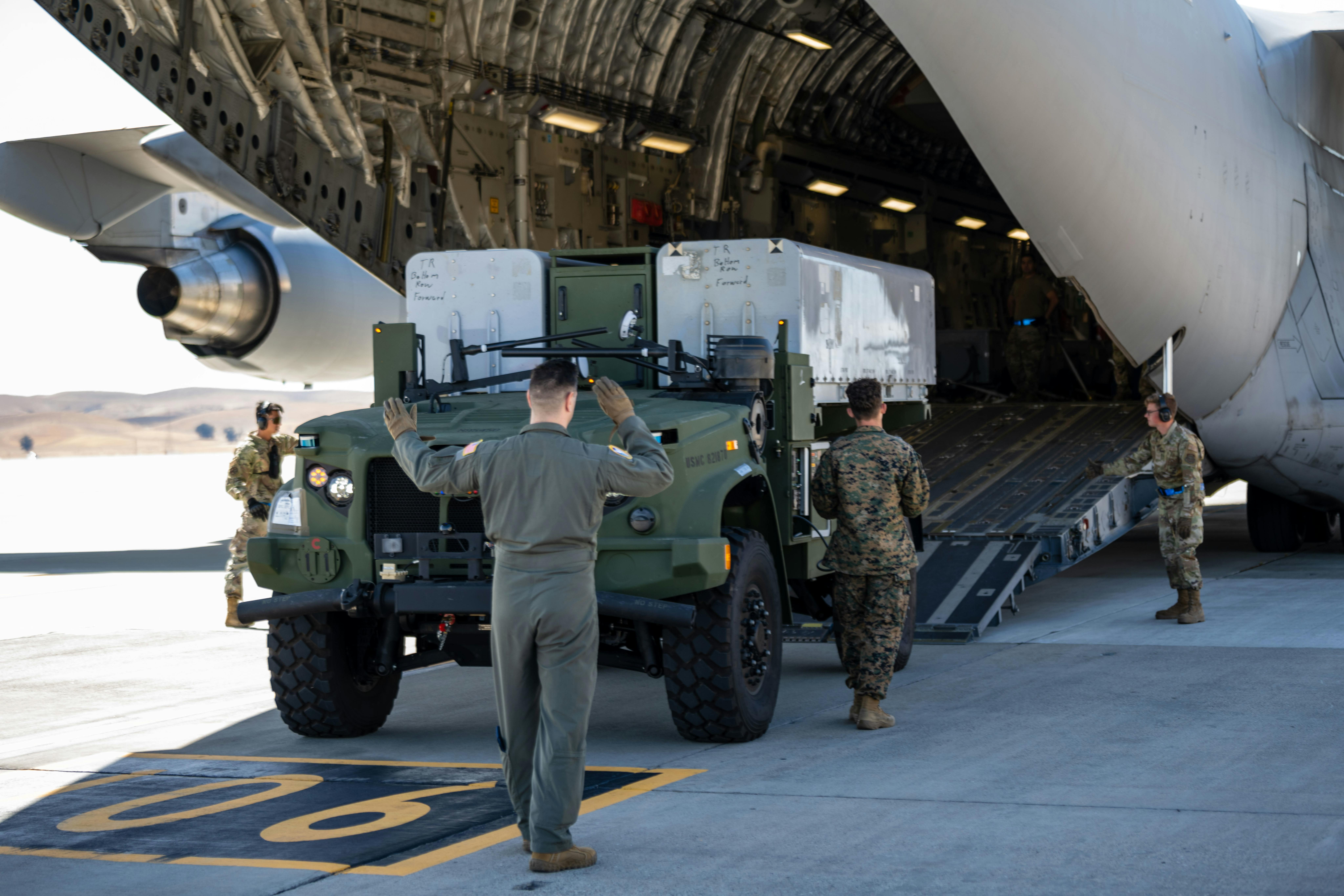 A U.S. Marine maintenance technician backs a Navy/Marine Corps Expeditionary Ship Interdiction System (NMESIS) launcher onto a C-17 Globemaster III at Travis Air Force Base, Calif., in September 2023.