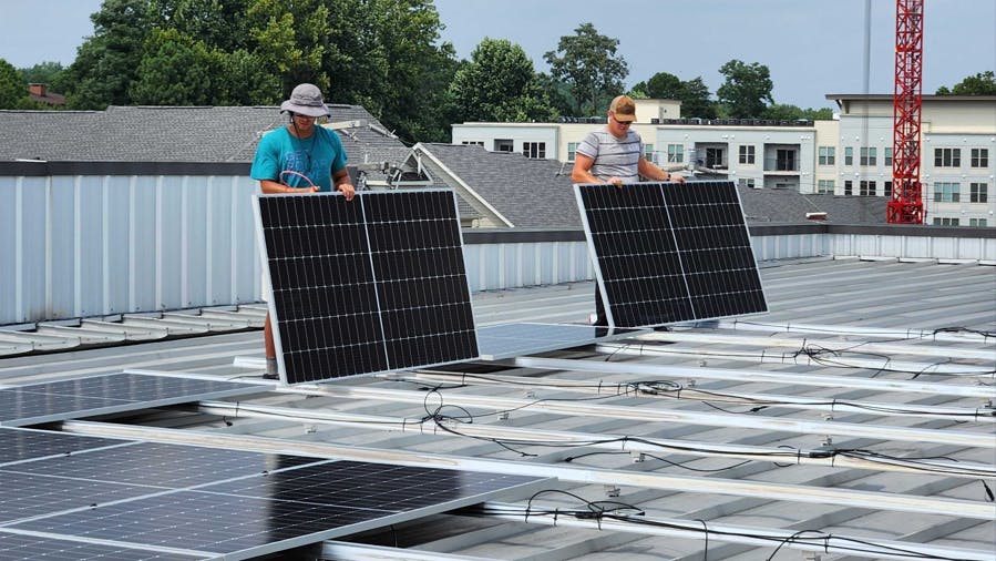 Solar installers wire-managing commercial panels on a self-storage facility in Virginia. Image credit Virtue Solar