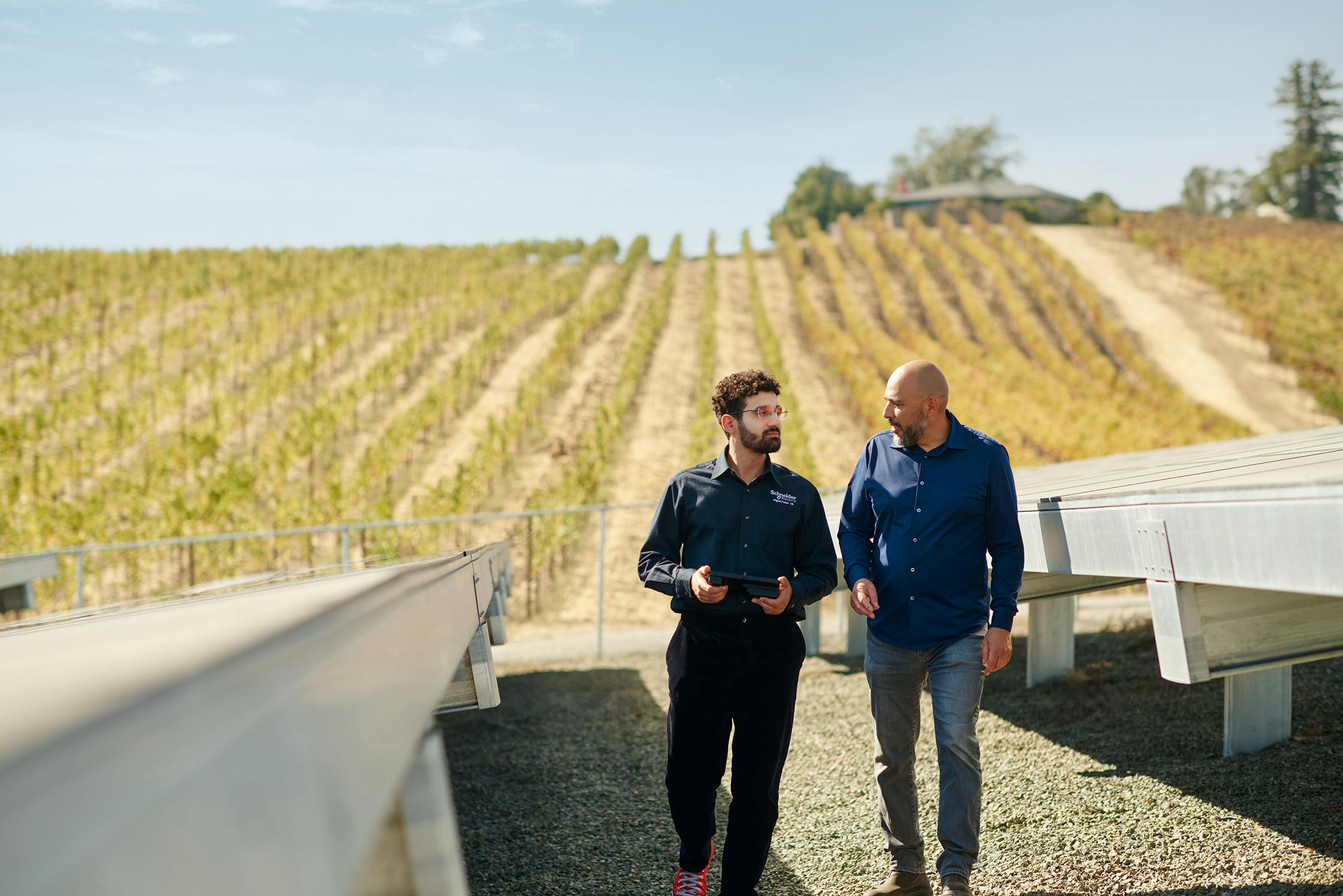 Yassine Askri, microgrid specialist with Schneider Electric (left) walks and chats with Abel Lopez, facilities manager of the Napa winery Domaine Carneros, while surveying the winery's solar and battery storage microgrid.