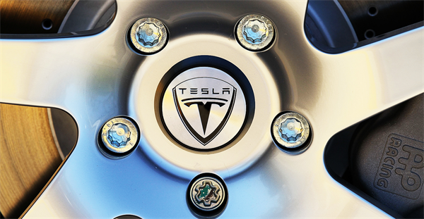Telsa logo surrounded by lug nuts on wheel