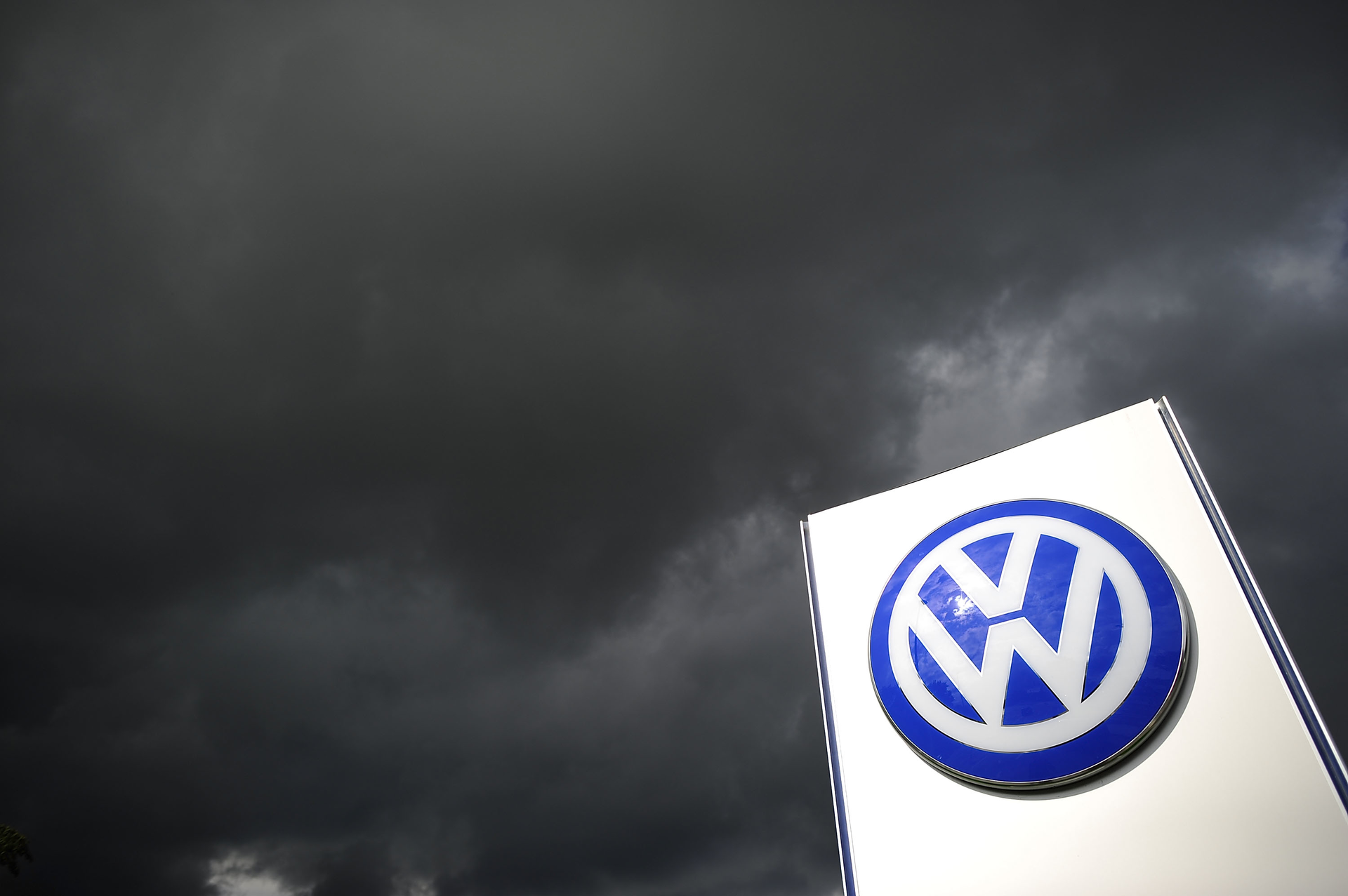 Volkswagen logo on sign under dark clouds