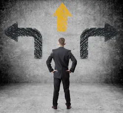 Man in suit standing in front of arrows pointing multiple directions Man in suit standing in front of arrows pointing multiple directions