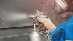 Worker spraying anti-corrosion coating on metal. Worker spraying anti-corrosion coating on metal.