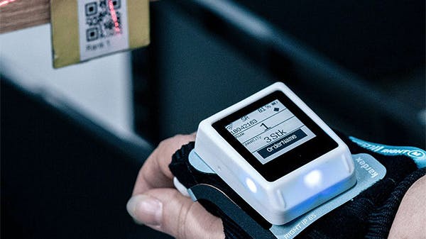Kardex Wearable Task Assistant for picking operations in use on employees wrist scanning a barcode
