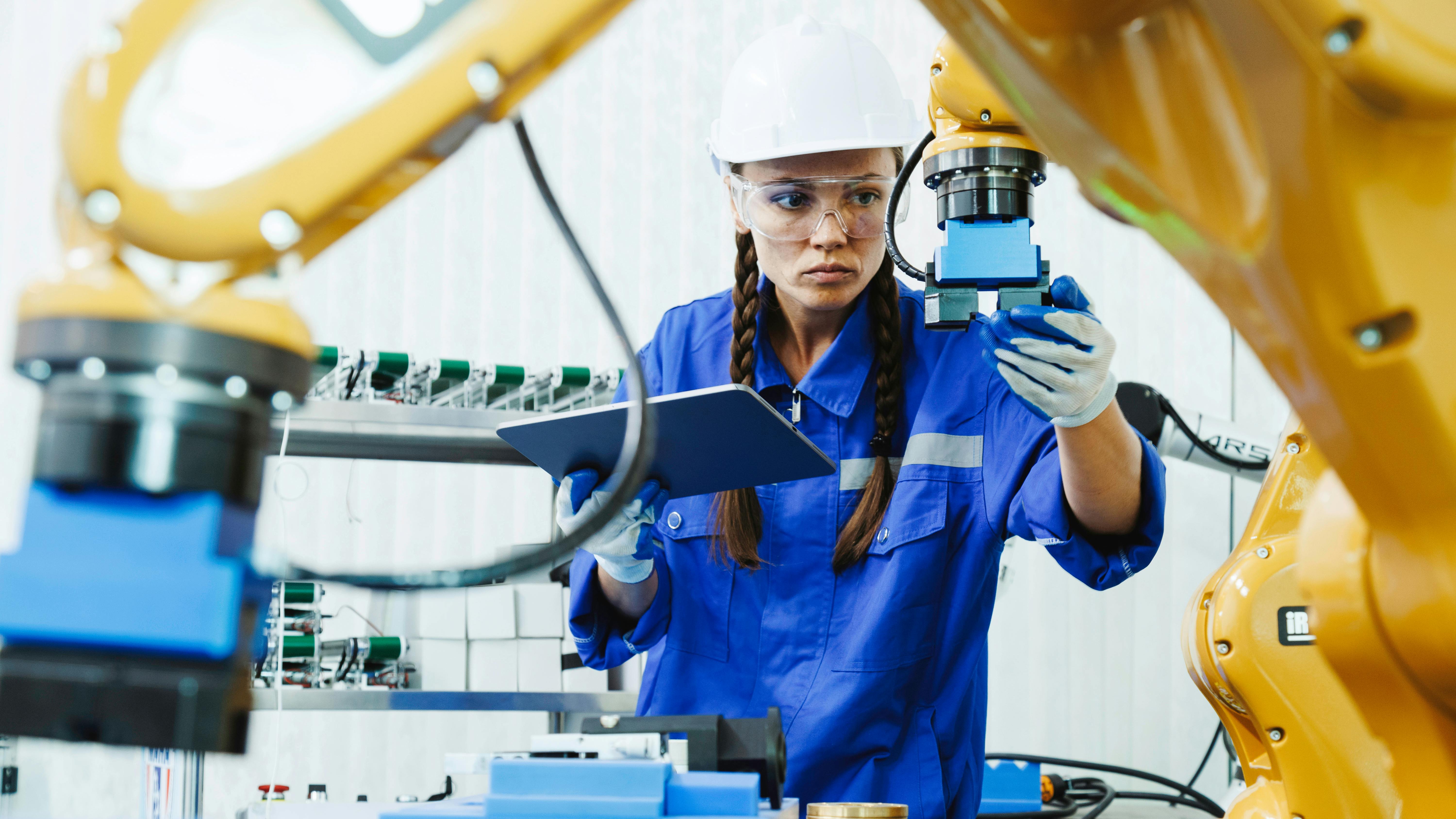 female automation machine engineer student inspecting control robot arm