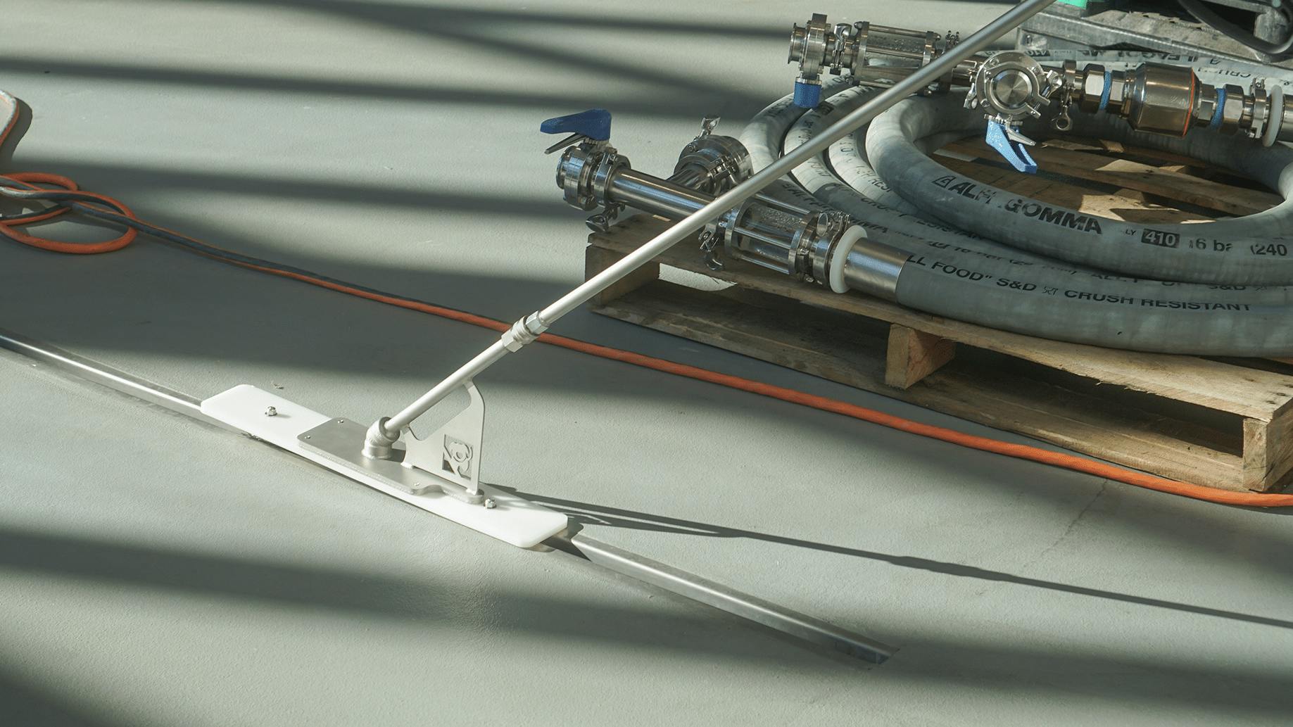 Slot dog drain cleaning tool in use on grey floor