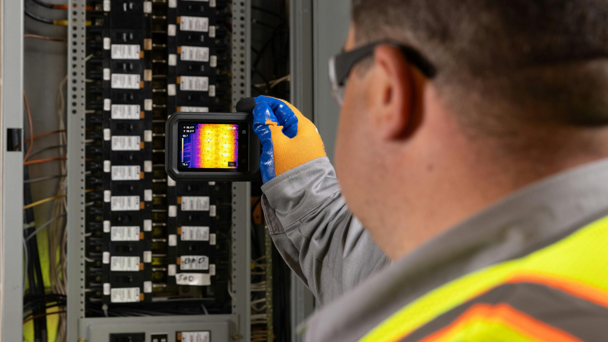 Worker inspecting electrical panel with Flir C8 thermal imaging camera
