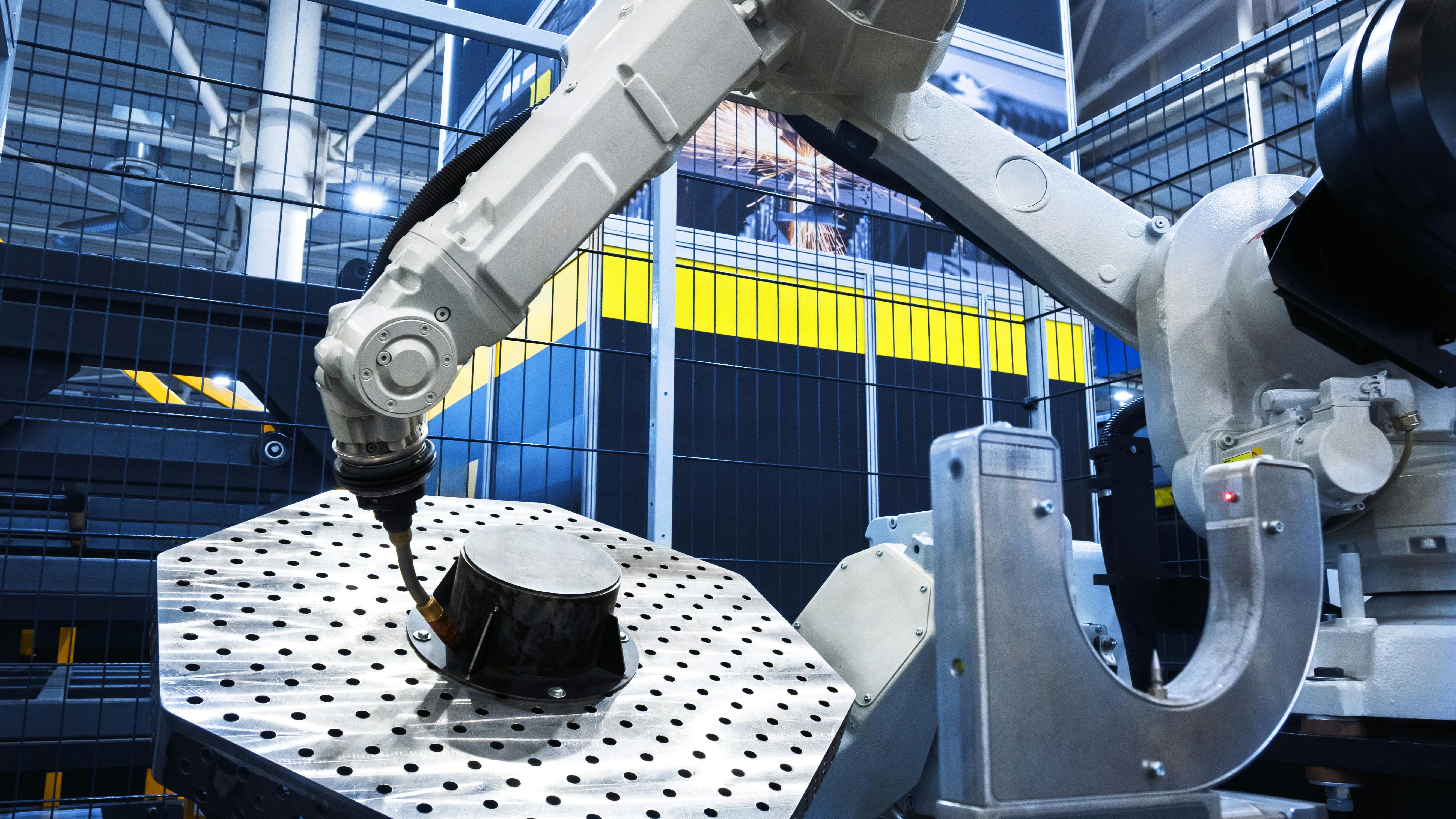 Robotic arm performs automated work on a metal part in a modern industrial factory.