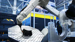 Robotic arm performs automated work on a metal part in a modern industrial factory. Robotic arm performs automated work on a metal part in a modern industrial factory.
