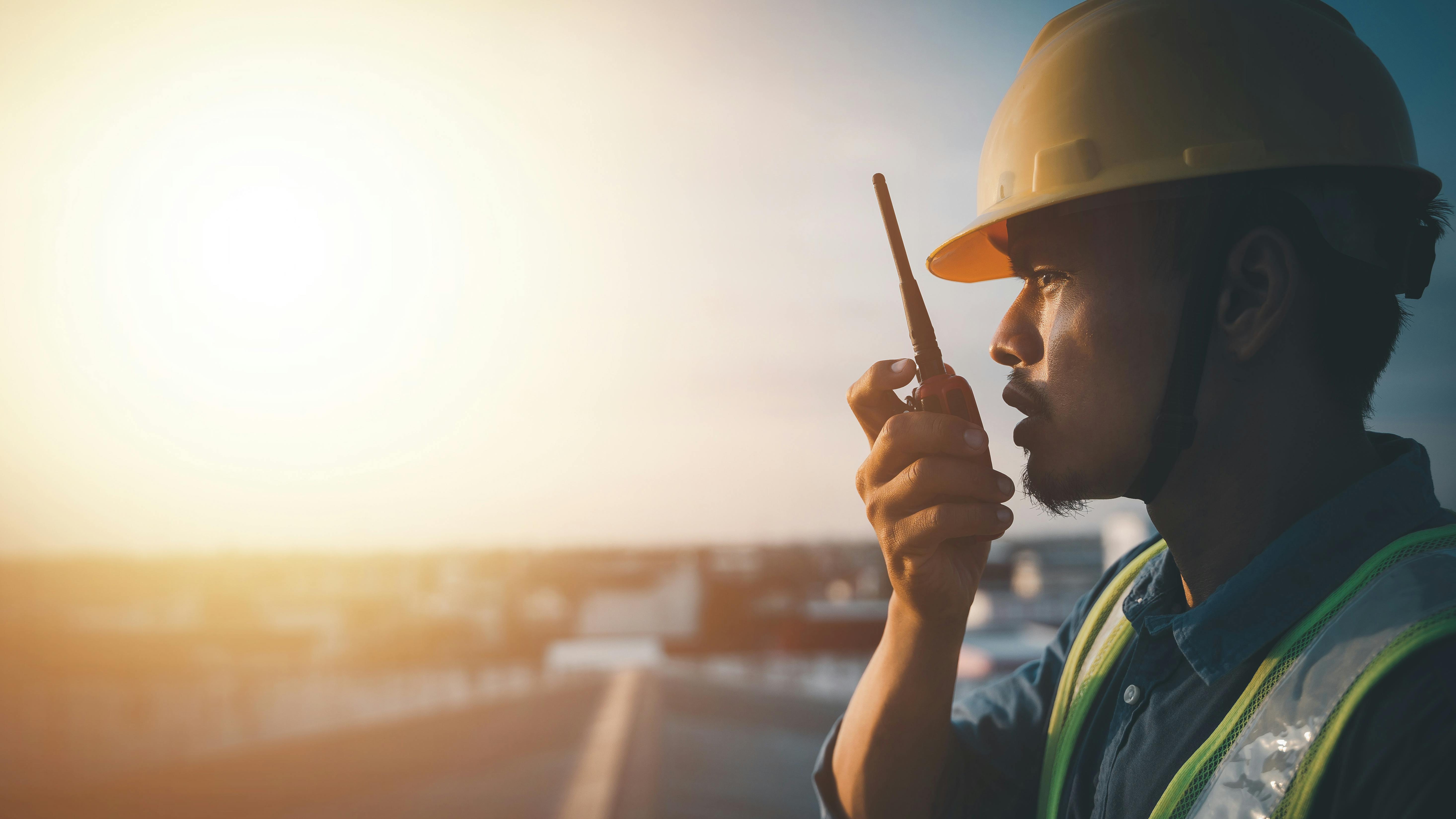 Worker in hard hat using walkie talkie