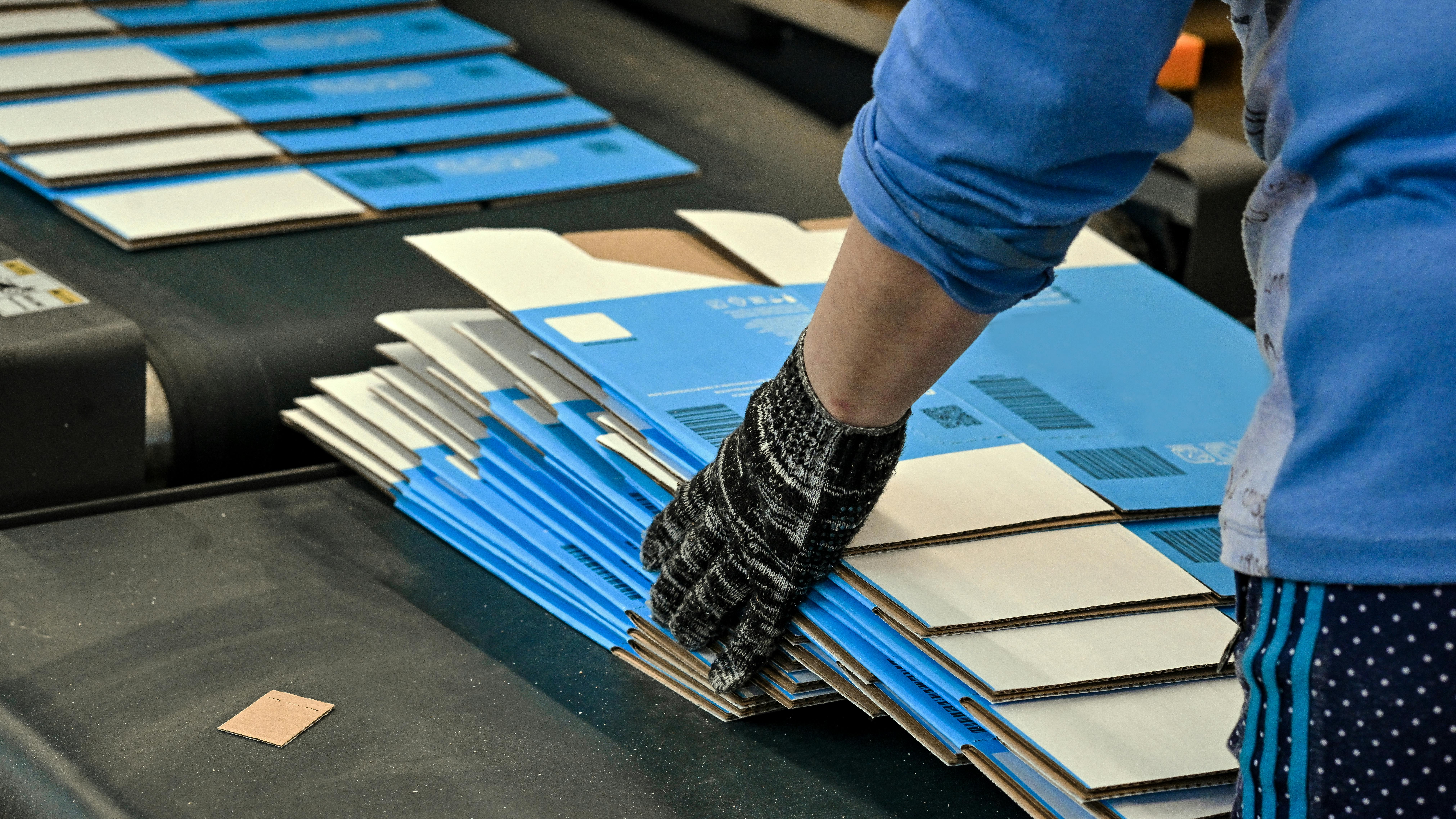 Worker gathering printed, flat carboard boxes ready for assembly off the line.