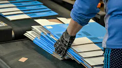 Worker gathering printed, flat carboard boxes ready for assembly off the line. Worker gathering printed, flat carboard boxes ready for assembly off the line.