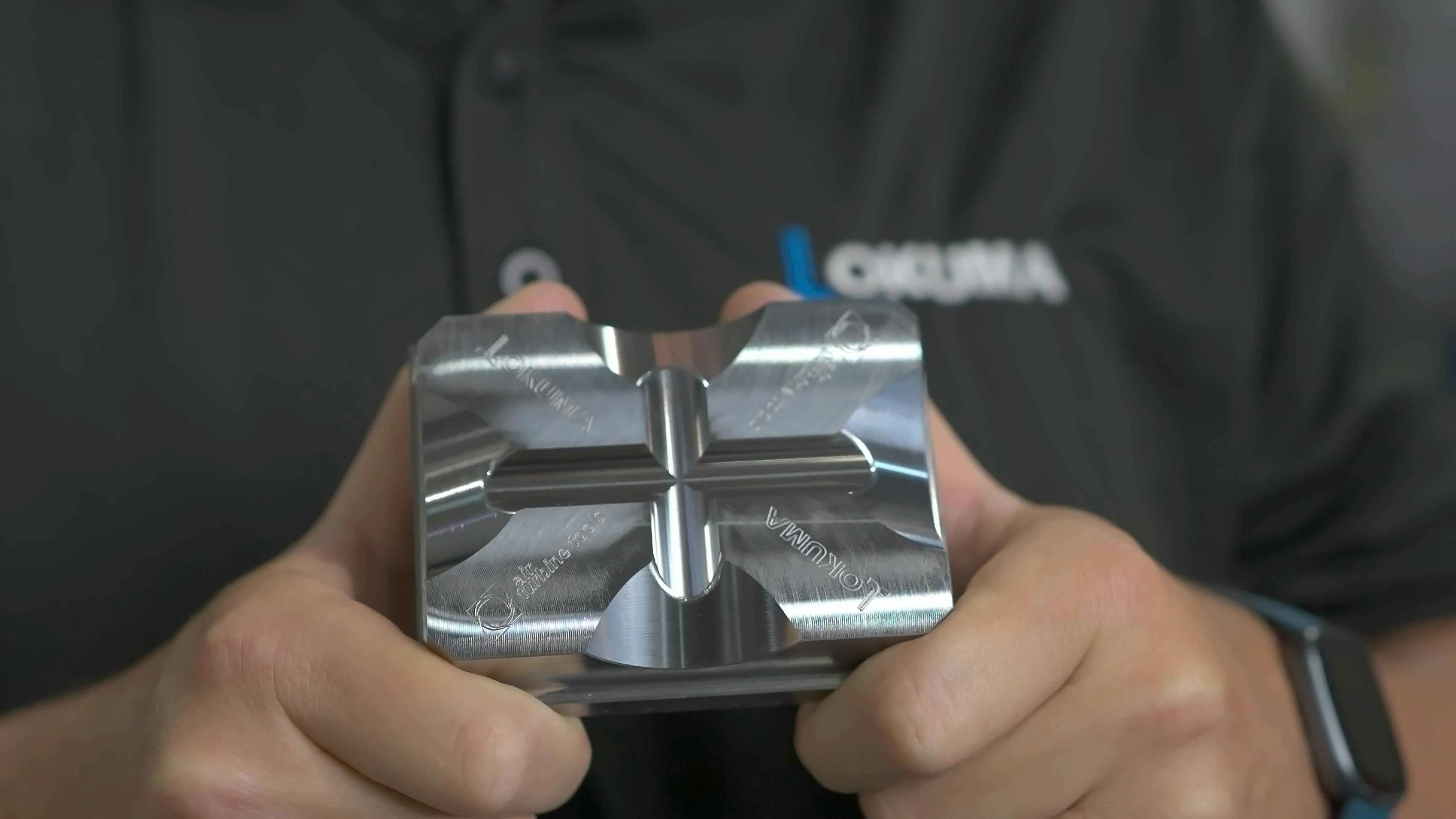 Okuma worker holding an Okuma part made with Air Turbine Technology tools.
