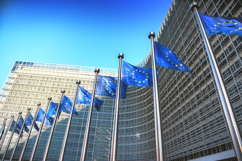 Waving EU flags in front of European Commission in Brussels, Belgium.