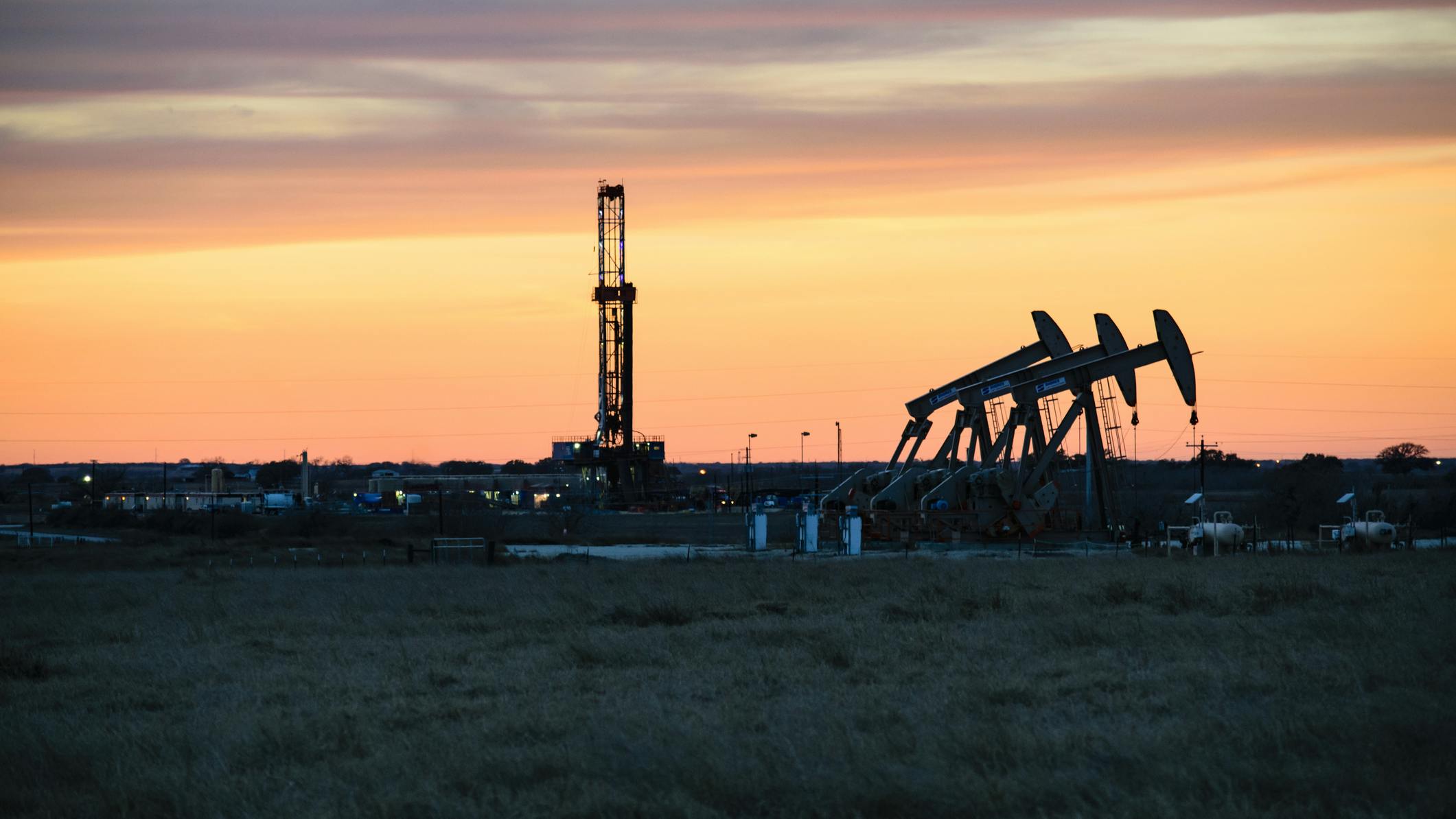 Shale oil drilling rig and pumpjacks at sunset