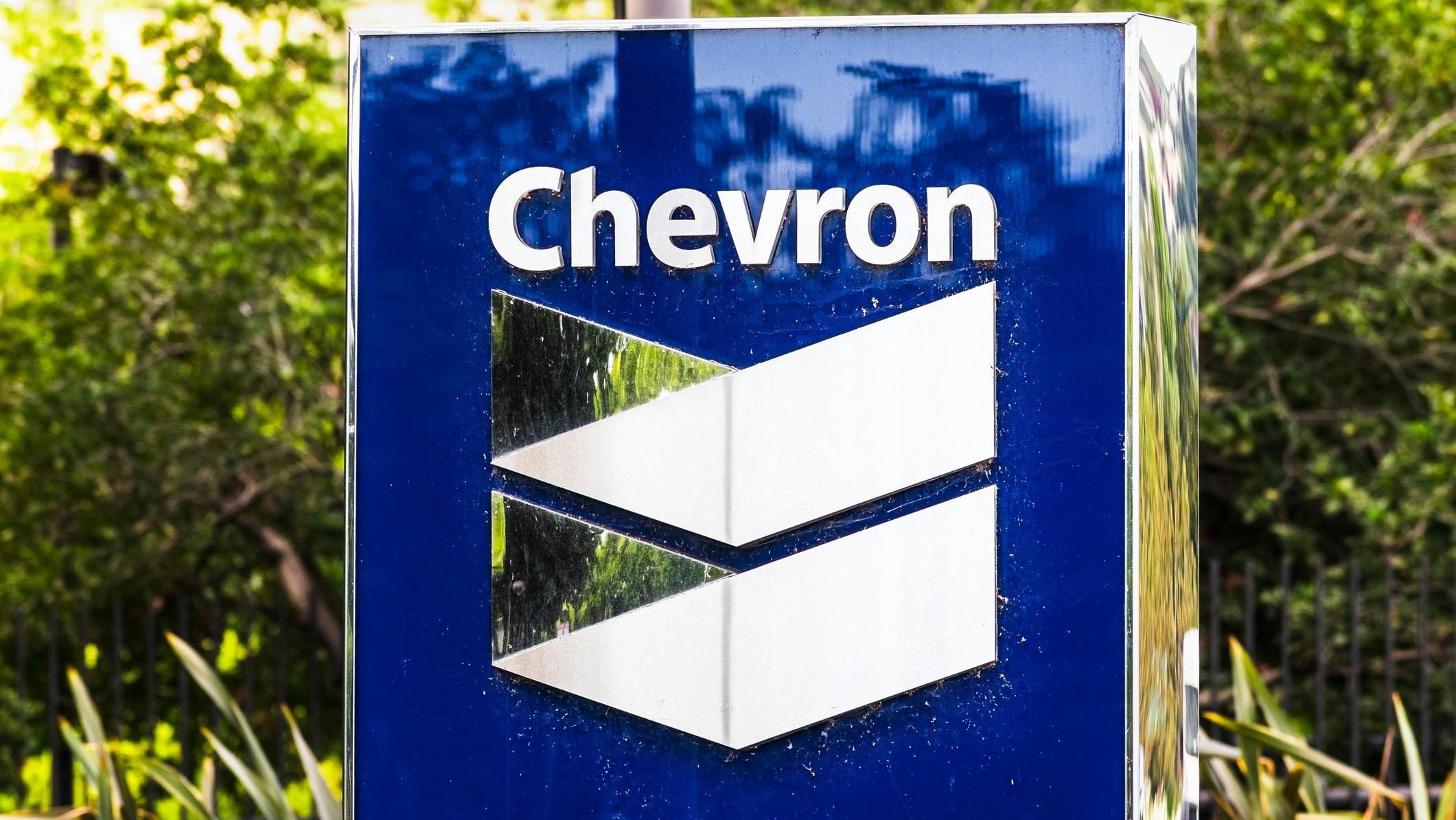 Chevron logo on sign with bushes in background