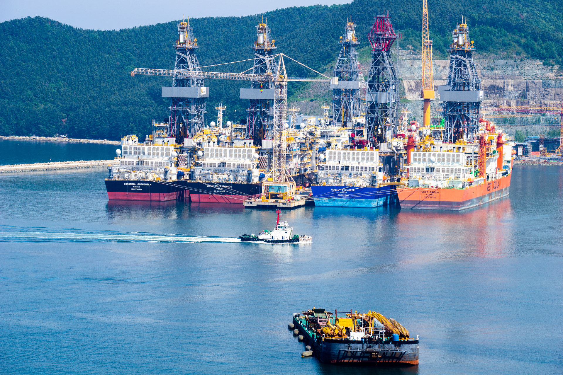 Tugboat sails past drill ships near the DSME shipyard in Okpo city, South Korea.