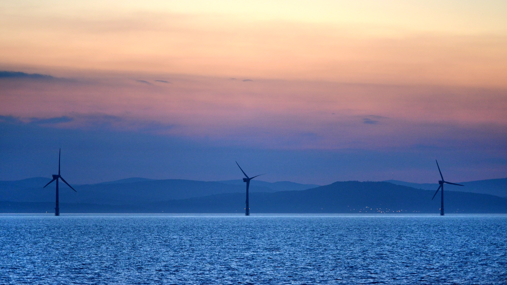 Offshore wind turbines operate at sunset off the Irish coast.