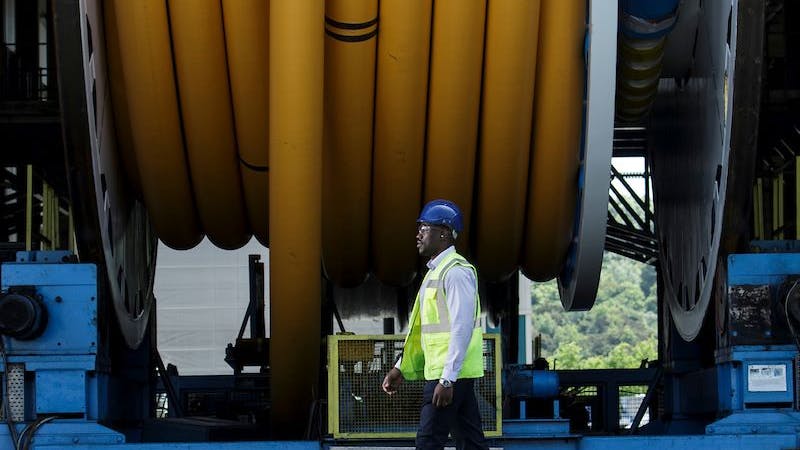 A worker walks past a spool of Baker Hughes flexible pipe at the company's Newcastle upon Tyne, UK facility.