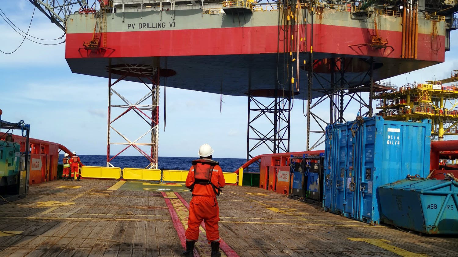 Marine crew get ready to work near jackup rig to receive cargo lift by crane operator