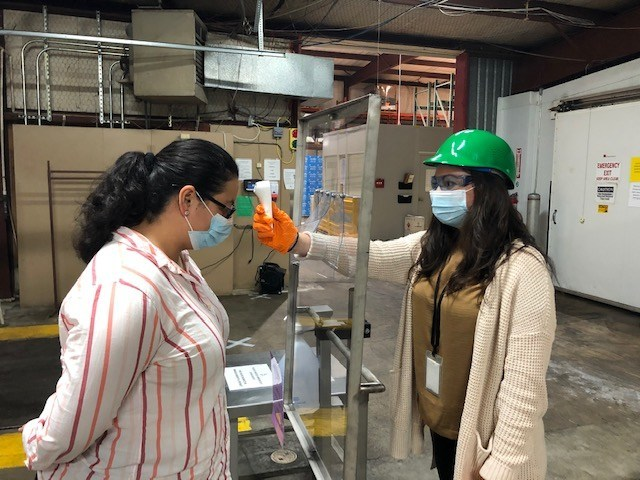 Utilizing infrared non-contact temperature devices, trained testers check the temperatures of associates entering a Perdue Farms facility in Schulenberg, Texas.